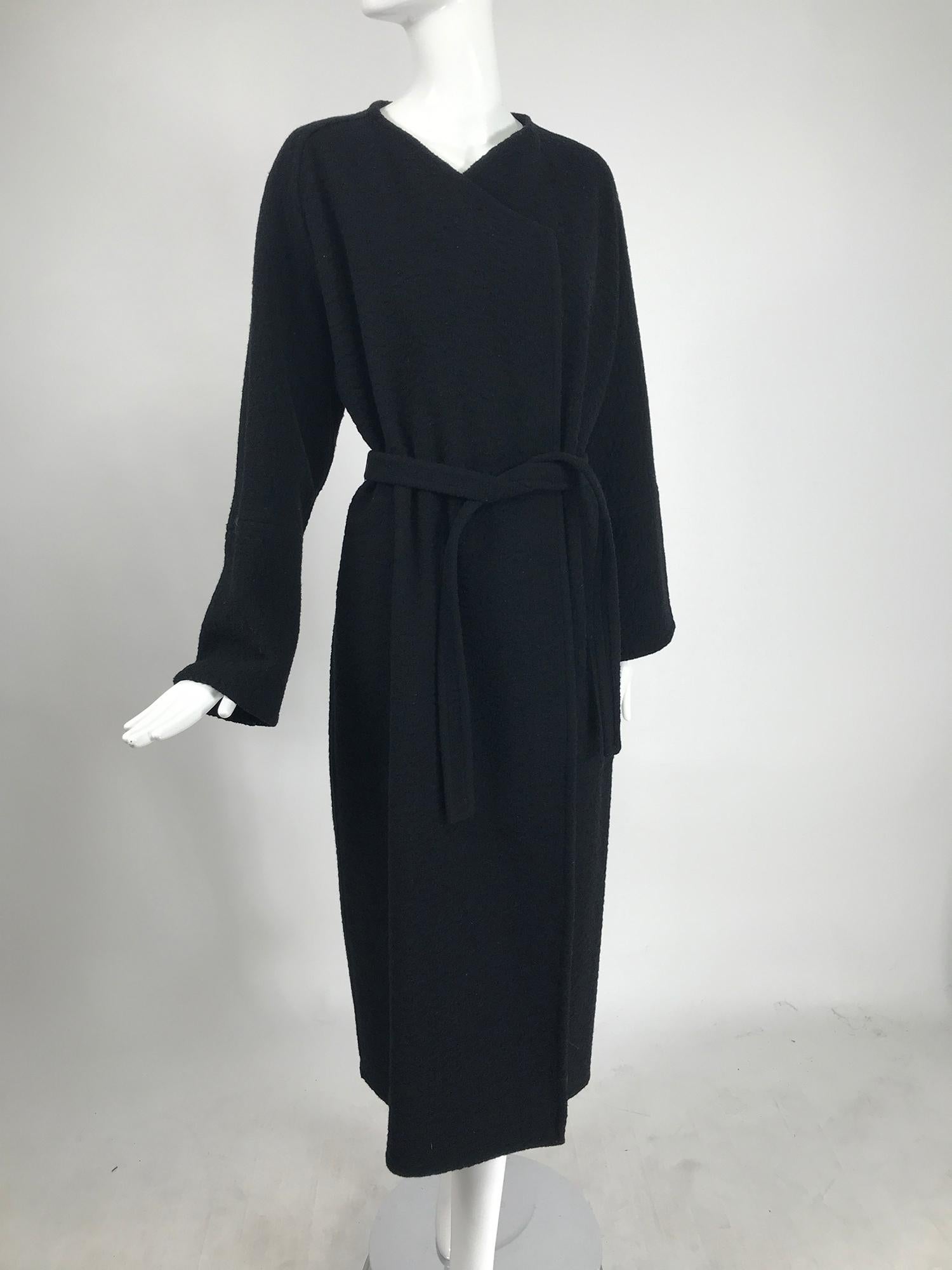 Yeohlee black textured double face wool wrap coat from the 1990s. Unlined coat with an angled shape neckline, wrap coat with self belt. Long sleeves have horizontal stitching mid way and can be turned back for a cuff. Below knee length coat has a