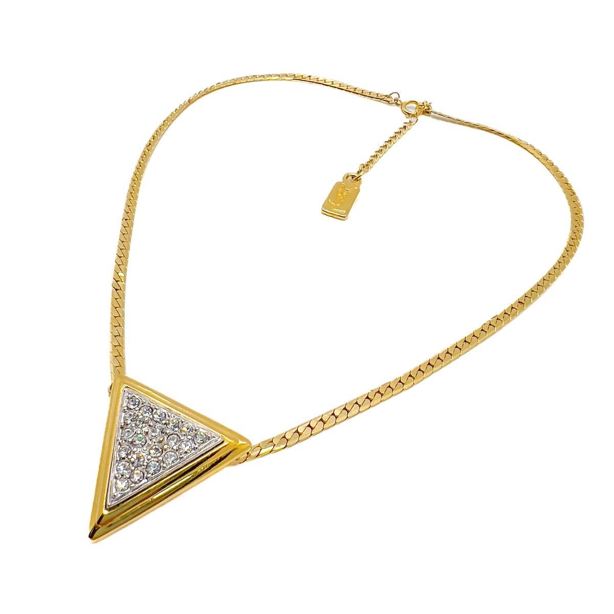 A Vintage YSL Geo Necklace featuring a flattened curb chain adorned with a geometric design pendant lavishly embellished with crystals. Pure contemporary chic from the ultra stylish House of YSL.

In 1961, following his time as Dior's Art Director,