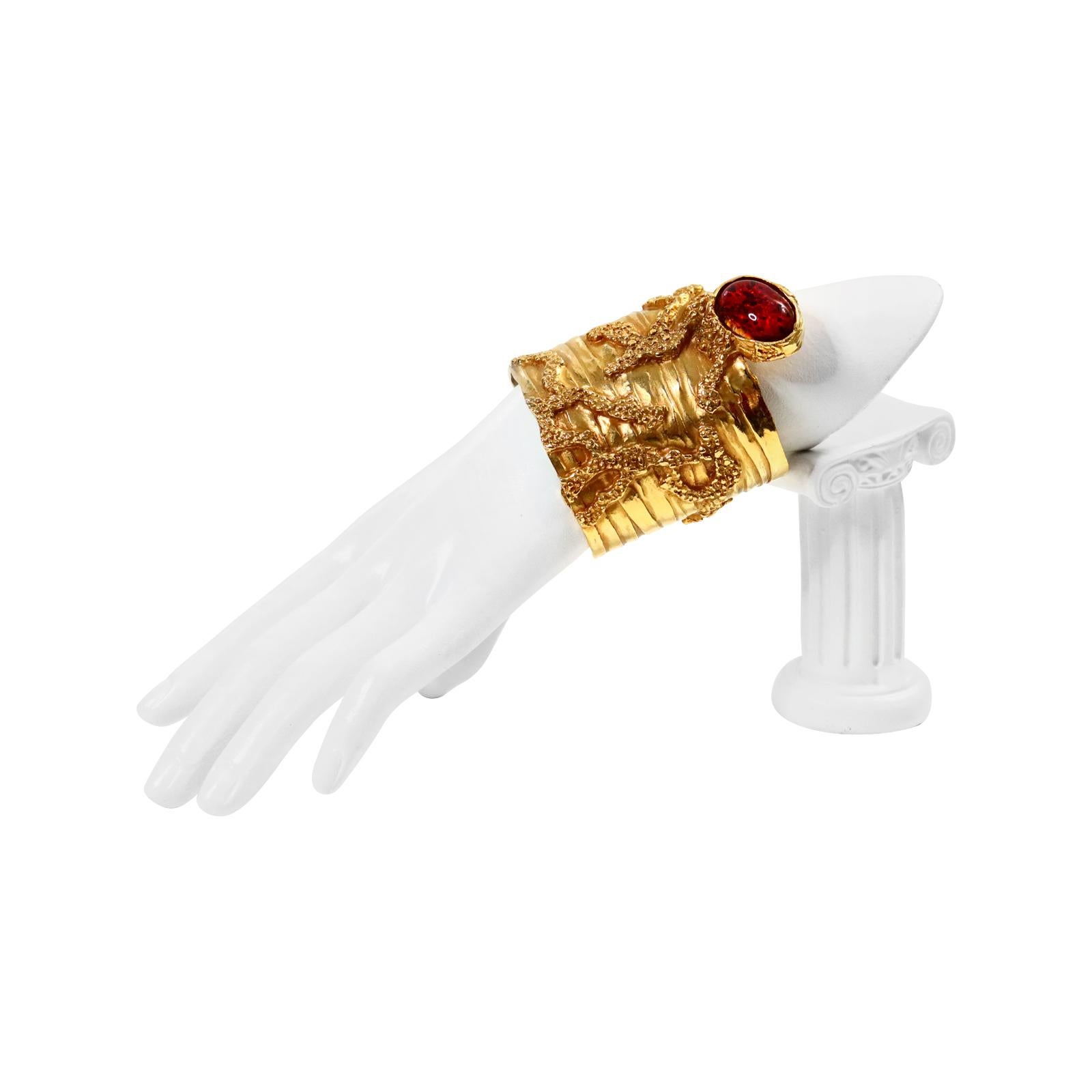 Vintage YSL Yves Saint Laurent Gold With Red Pate De Vere From the Collection Arty Circa 2000s.  This gorgeous Cuff has raised detail all over the cuff. Almost looks like creeping branches coming down and at the very end is the red pate de verre.  I