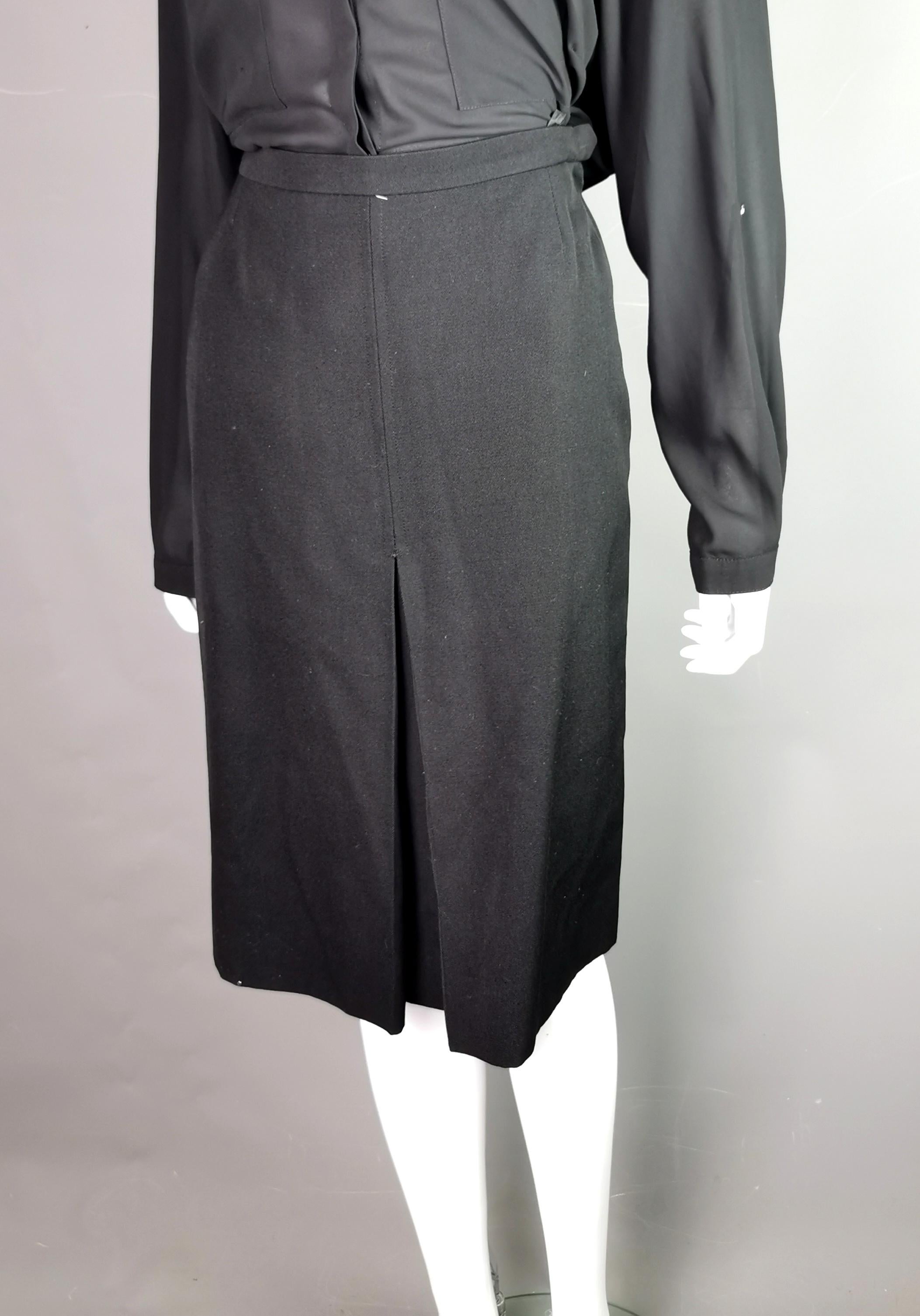 A stylish vintage YSL Rive Gauche black wool pleat front skirt.

It is a pencil style skirt with a pleat design to the front.

It fastens at the side with a metal hook fastening and a zip.

Perfect for the office or formal events.

Labelled for YSL
