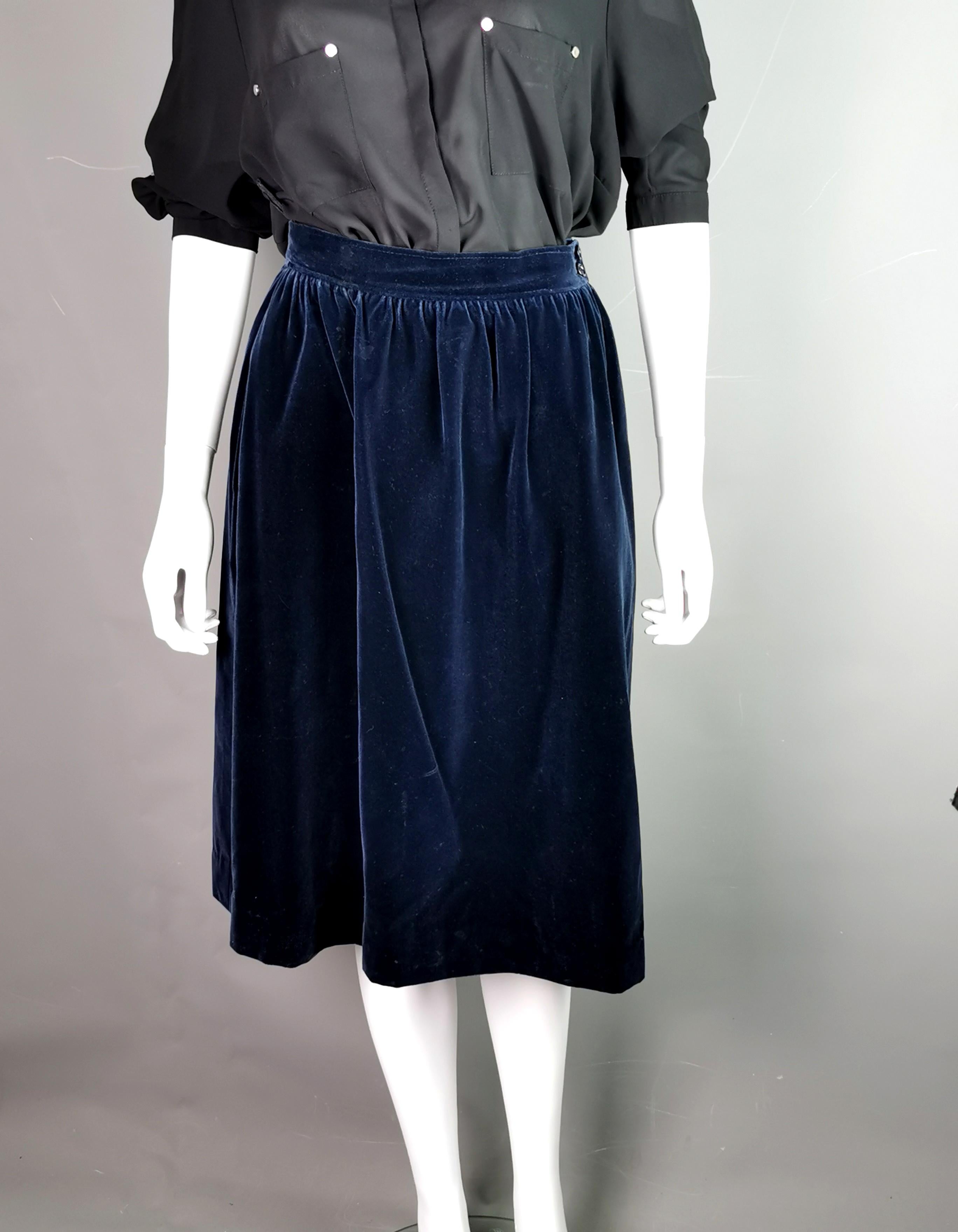 A stylish vintage YSL Rive Gauche navy blue velvet skirt.

It is a full skirt with a fitted waistband, a dark navy blue medium weight skirt that could make a great day to night transition.

It fastens at the side with two plastic buttons and a zip