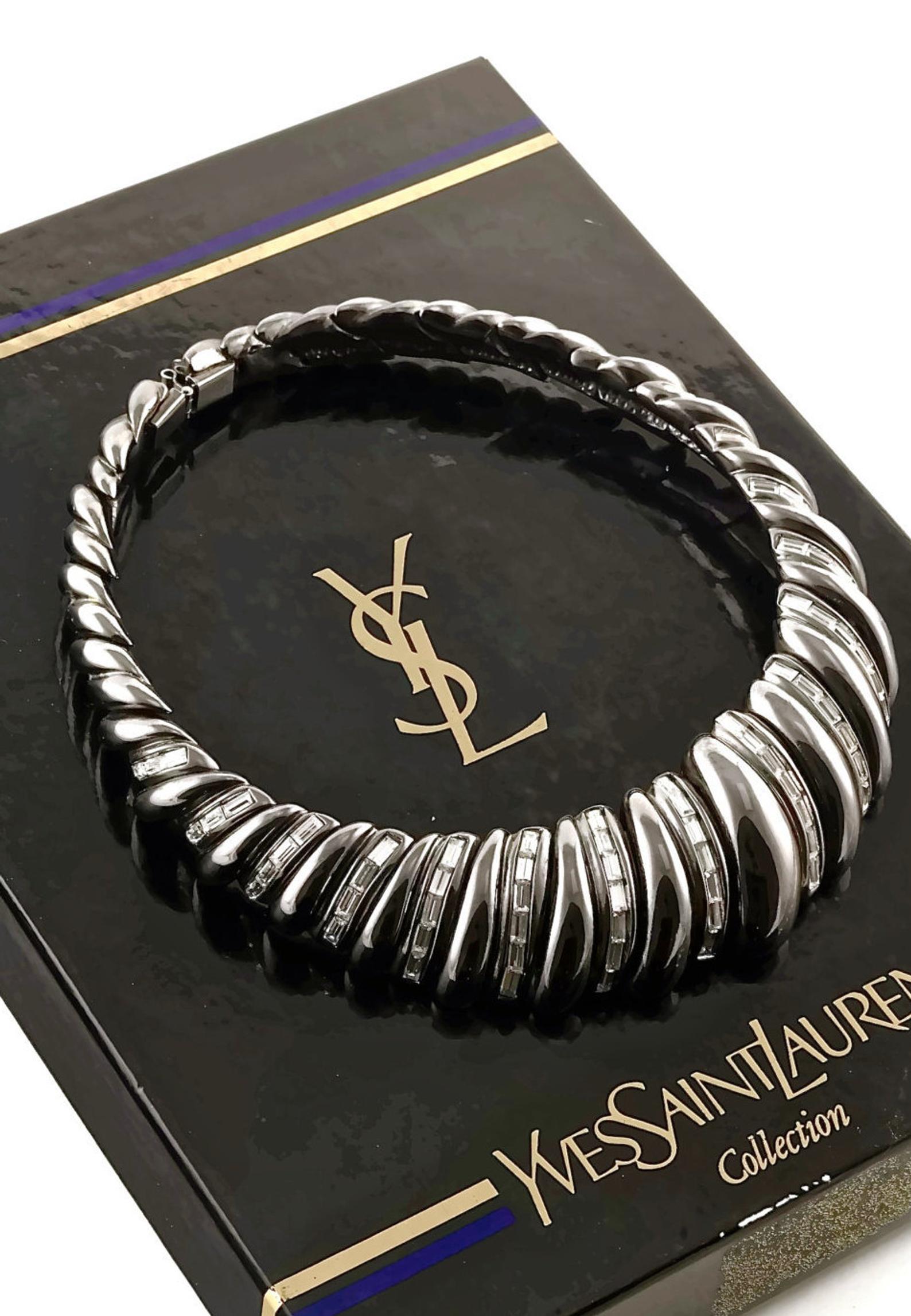 Vintage YSL Yves Saint Laurent Gunmetal Rhinestones Choker Necklace

Measurements:
Height: 1 5/8 inches (4.12 cm)
Inside Circumference: 14 2/8 inches (36.19 cm)

Features:
- 100% Authentic YVES SAINT LAURENT.
- Gunmetal choker embellished with