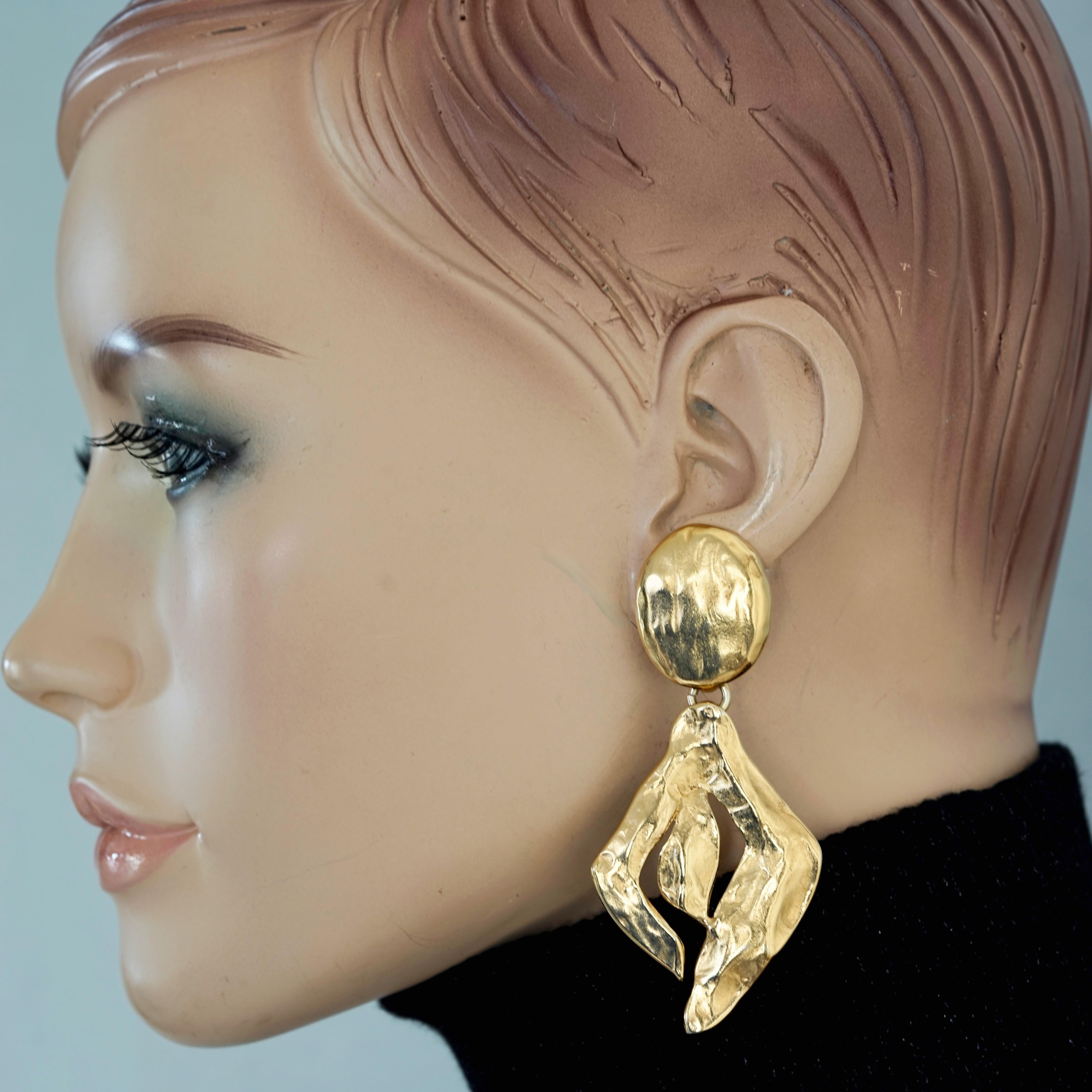 Vintage YSL Yves Saint Laurent Hammered Stylized Drop Earrings

Measurements:
Height: 3 1/8 inches (7.93 cms)
Width: 1 4/8 inches (3.81 cms)

Features:
- 100% Authentic YVES SAINT LAURENT.
- Hammered stylized drop earrings.
- Gold tone.
- Signed YSL