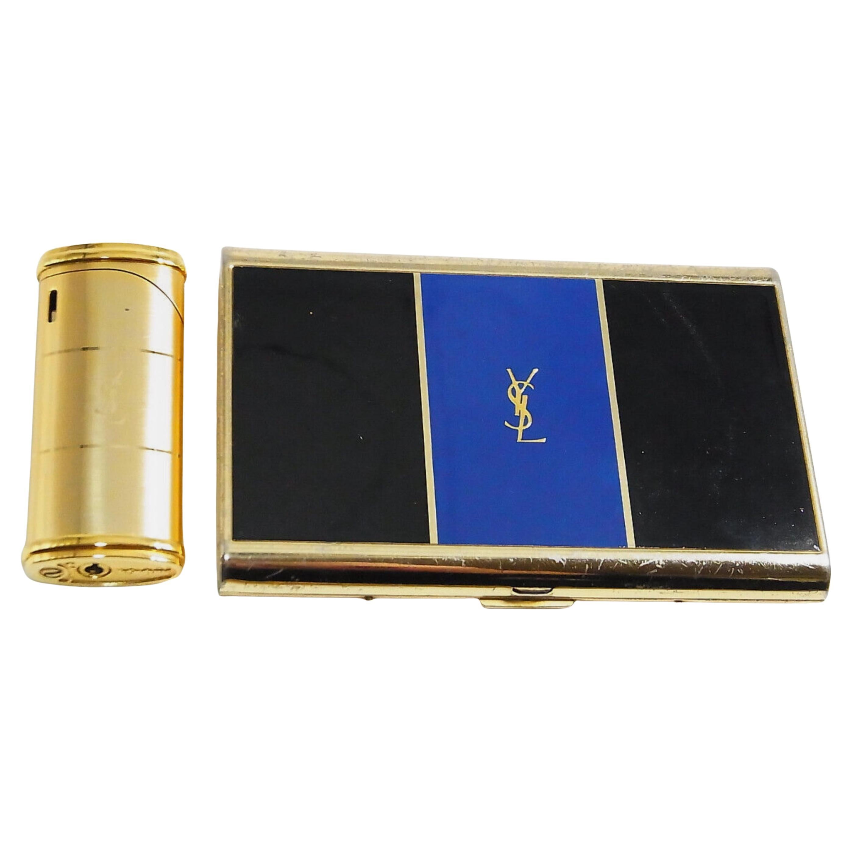 Vintage “YSL” Yves Saint Laurent Retro Cigarette Case & Lighter Set 
“Circa 1980”
“YSL” Yves Saint Laurent retro cigarette case and lighter 
Logo Cigarette Case Gold Black Blue
The case is in mint condition. It has never been used. 
The clasp snaps