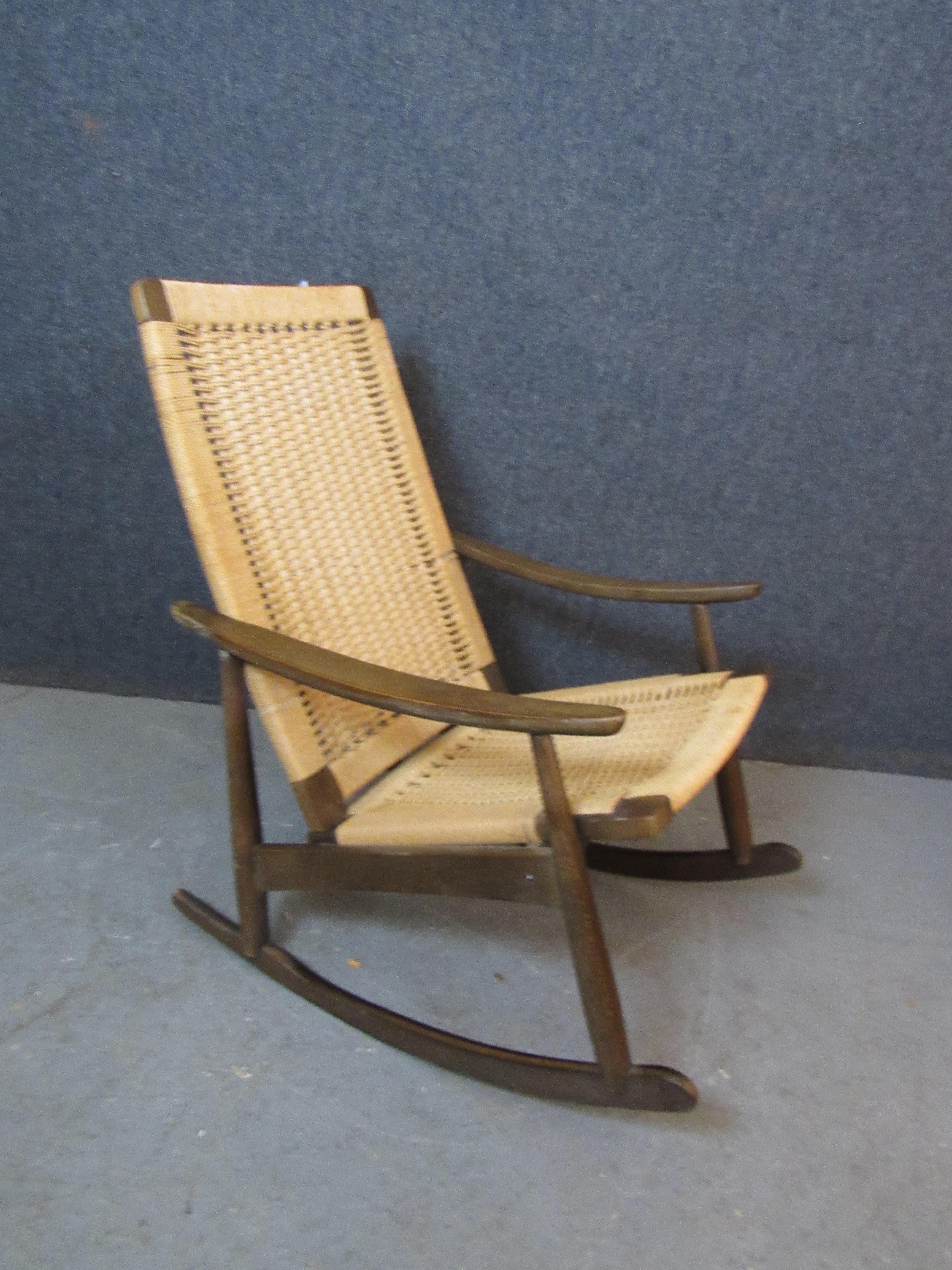 Dai un tocco vintage all'arredamento della tua casa con questa bella sedia a dondolo intrecciata. Costruita nell'ex Jugoslavia ma ispirata ai maestri del design danese come Hans Wegner, questa comoda seduta combina l'aspetto moderno con