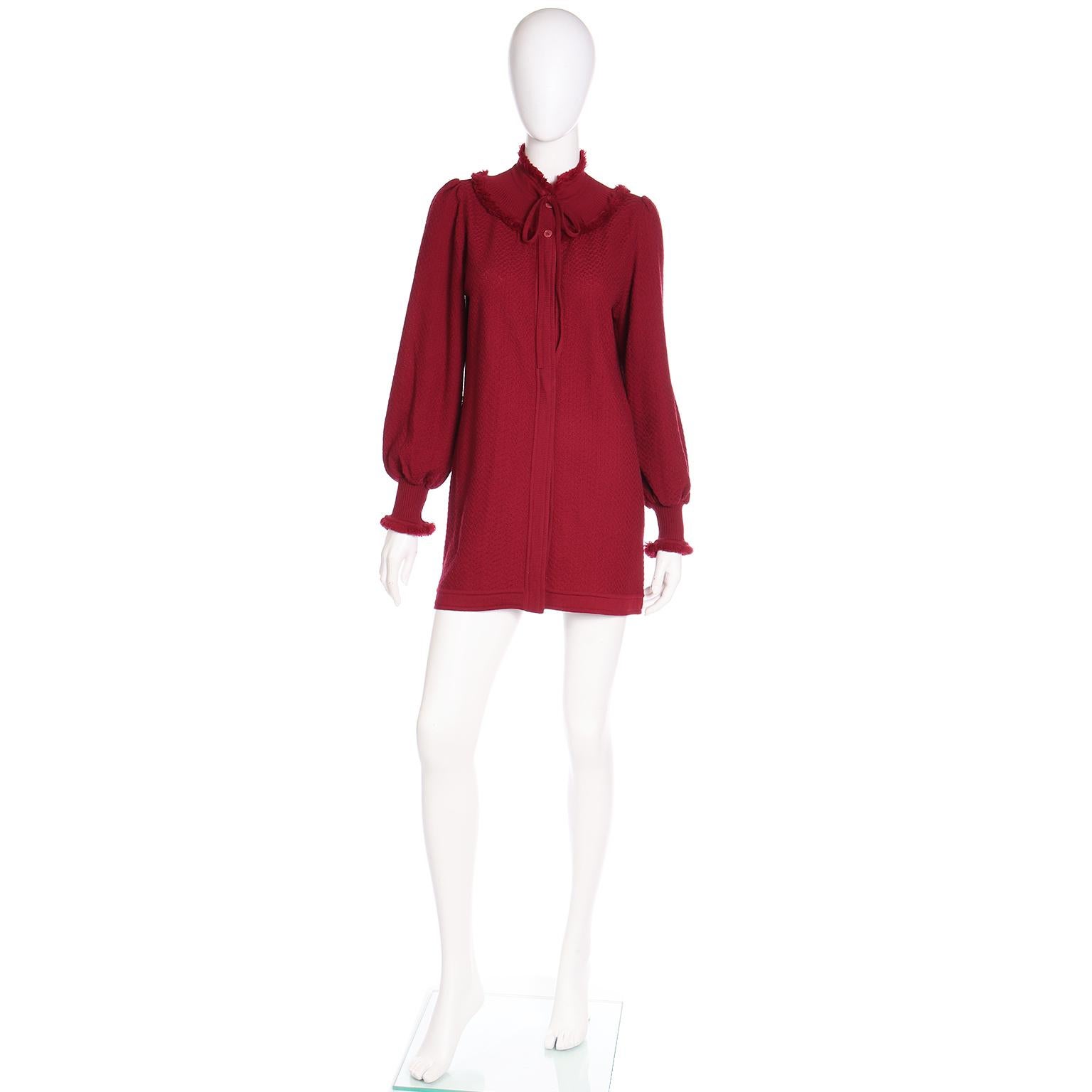 Dies ist eine große Vintage 1970's YSL Burgund rot Wolle stricken Pullover mit einem Fransen getrimmt Passe und Fransen an den Manschetten. Das Kleid wird im Nacken gebunden und ist oben mit zwei Knöpfen zu schließen. Die Schultern sind so