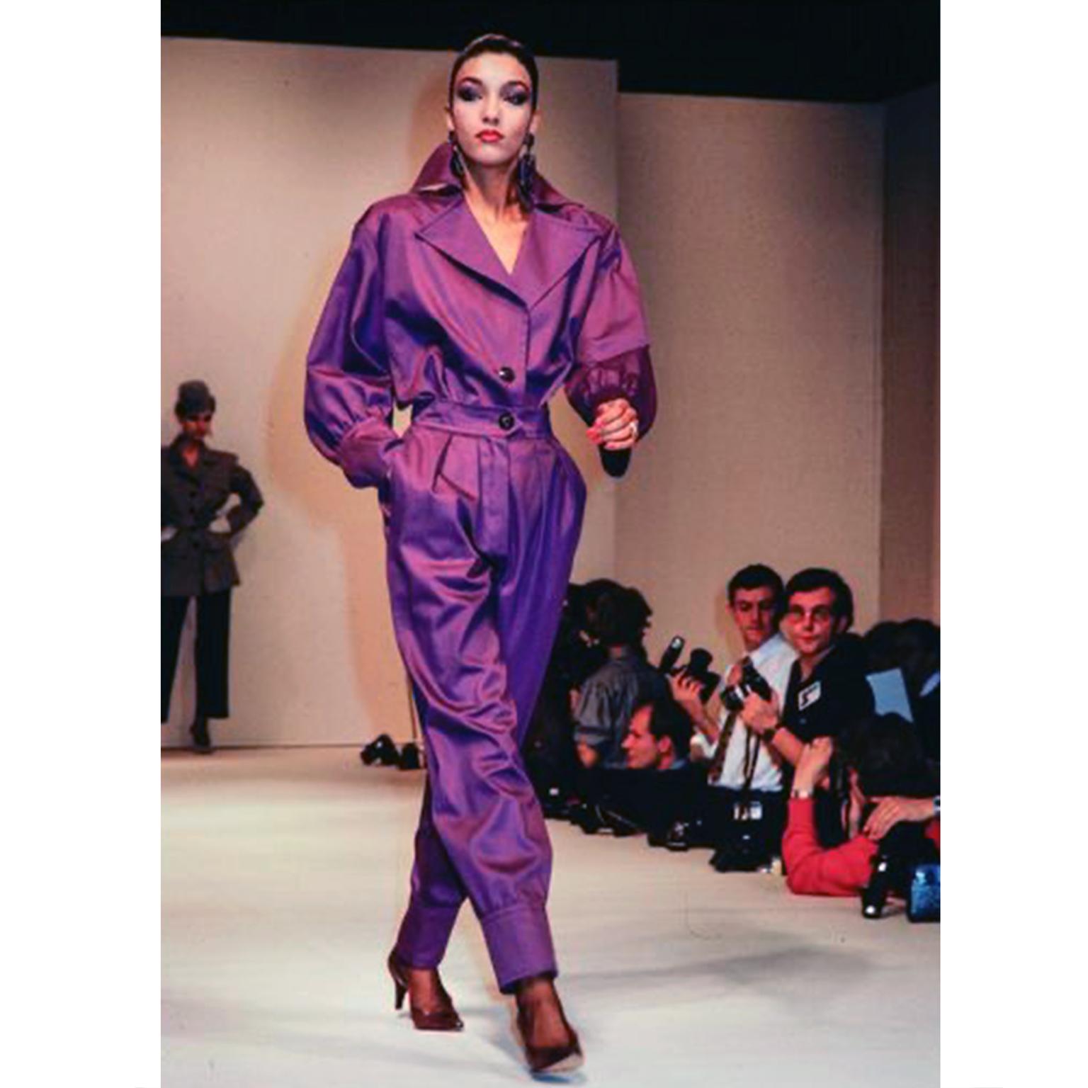 This is a fabulous Yves Saint Laurent runway documented 1985 2 piece outfit is made of sturdy purple cotton and it includes a jacket style shirt and a pair of high waisted trousers.

The jacket or top has long, puffy peasant sleeves, and a