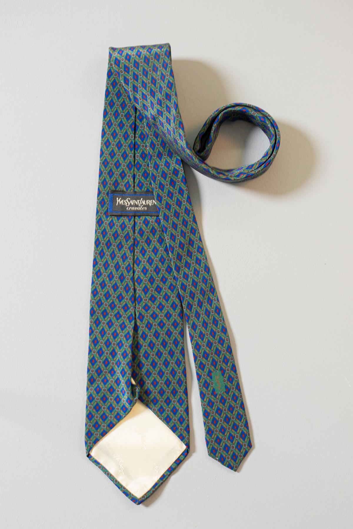 Fine et élégante, cette cravate vintage a été conçue par Yves Saint Laurent et elle est en toute soie. Ses motifs verts, bleus et rouges font de cette cravate un objet classe et élégant. Cette cravate est parfaite pour toutes les situations, du