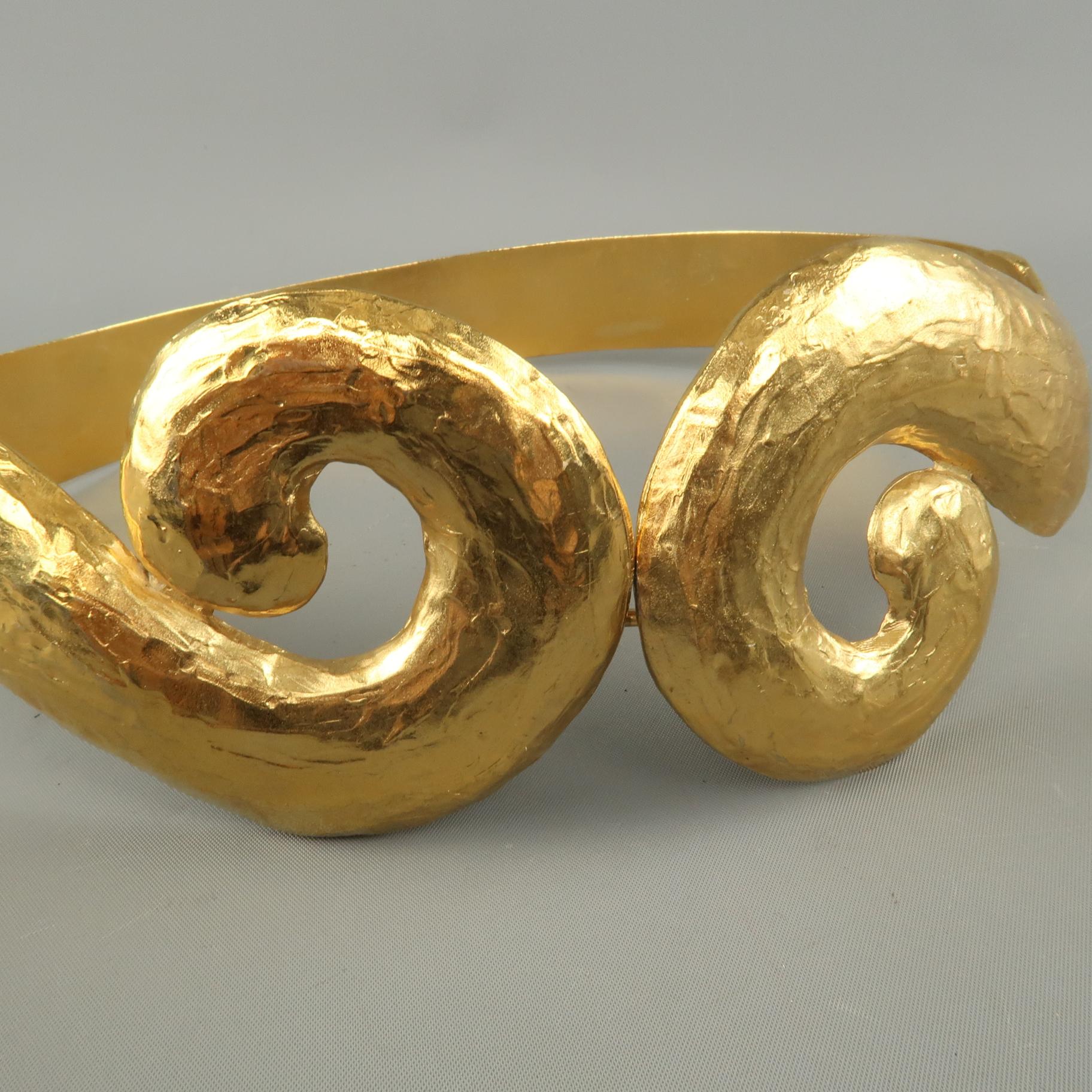 This rare vintage circa 1980's YVES SAINT LAURENT RIVE GAUCHE belt by legendary jewelry designer ROBERT GOOSEENS comes in yellow gold tone hammered rigid metal with a textured band, swirl motif front, and hook eye closure. Made in France.
