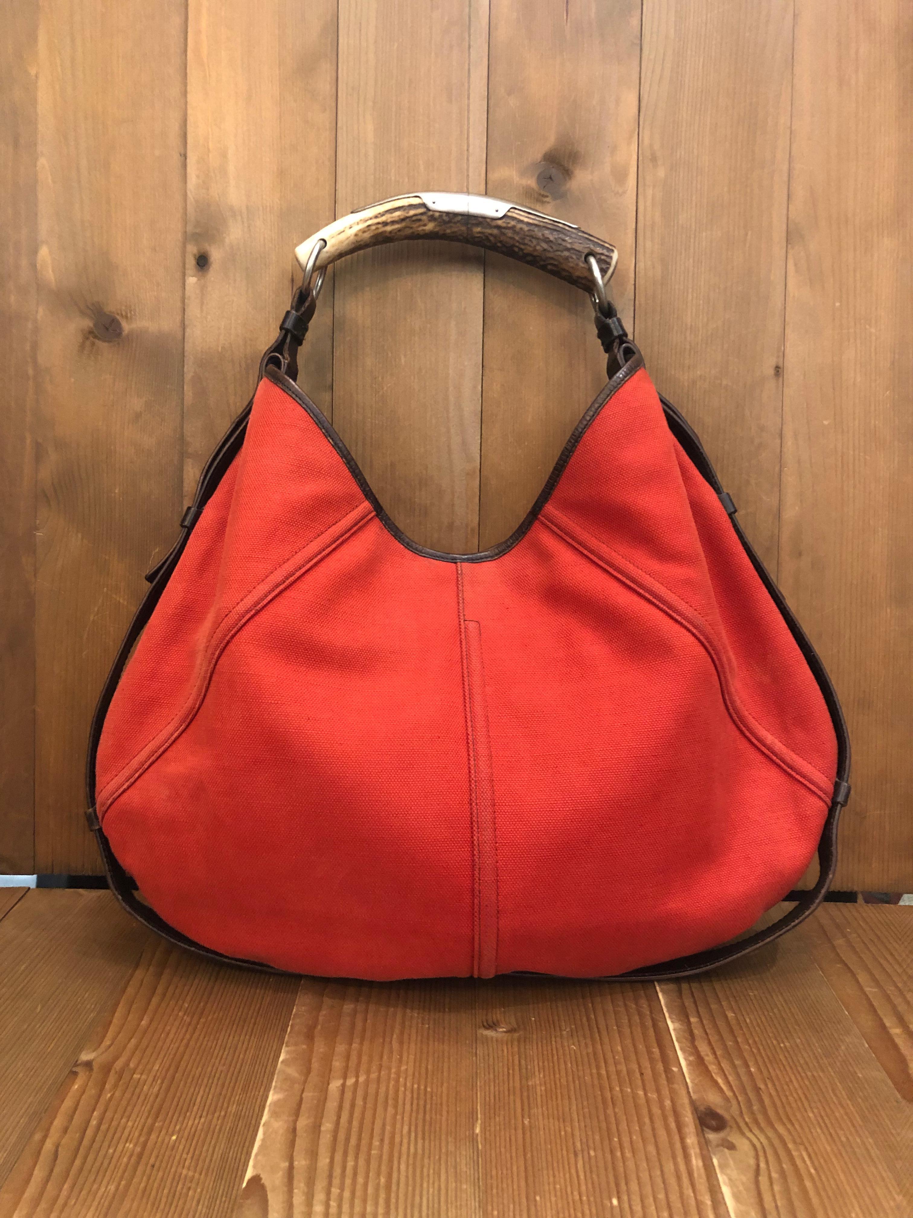 This iconic Yves Saint Laurent Mombasa hand bag from the 2000's Tom Ford era is crafted of canvas in orange and dark brown leather features a deer horn handle. Top magnetic snap closure opens to an un-lined orange canvas interior featuring one