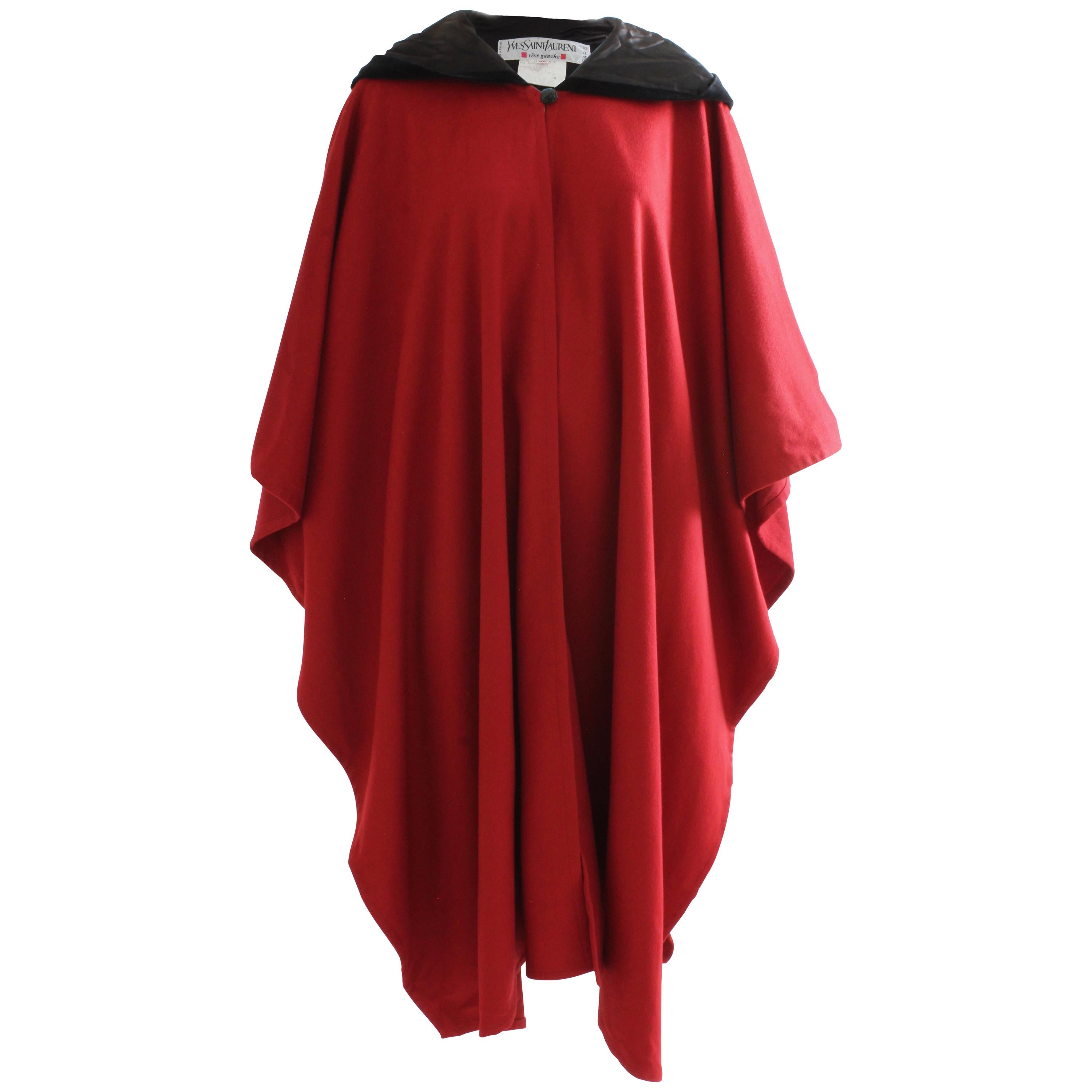 This cape is amazing and SO hard to find in this color! Made from a rich garnet red wool, it features a black silk velvet hood and insert panel on the back.  The cape is unlined, the hood is lined in black silk. Fastens with a single black button. 