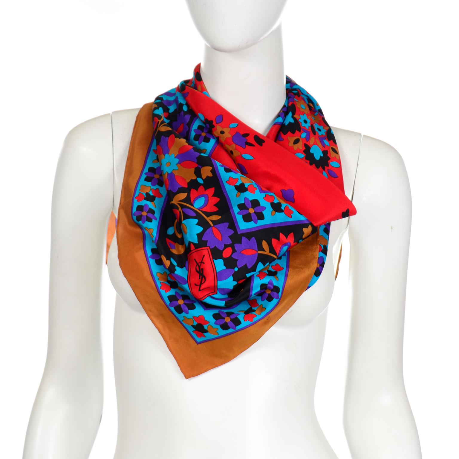 This beautiful, colorful Yves Saint Laurent vintage scarf is in rich shades of blue, red, black and purple with a copper brown border. The print depicts a folk floral design and the scarf measures 36