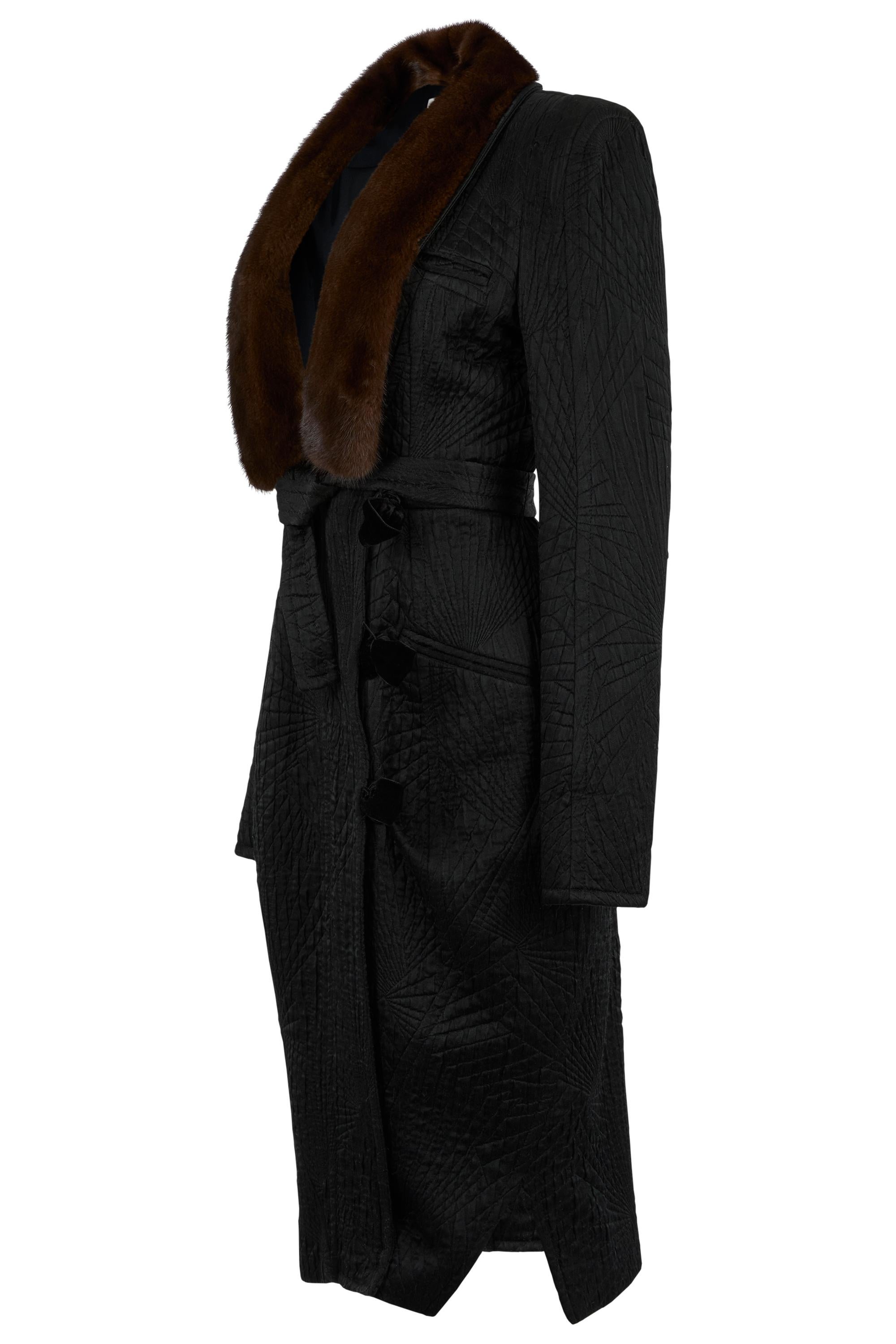 Collezione vintage Yves Saint Laurent Autunno/Inverno 2004,  Caratterizzato da una vestibilità strutturata e longilinea, da uno scultoreo jacquard nero con una sottile trama trapuntata, il modello è rifinito da un sontuoso collo di pelliccia marrone