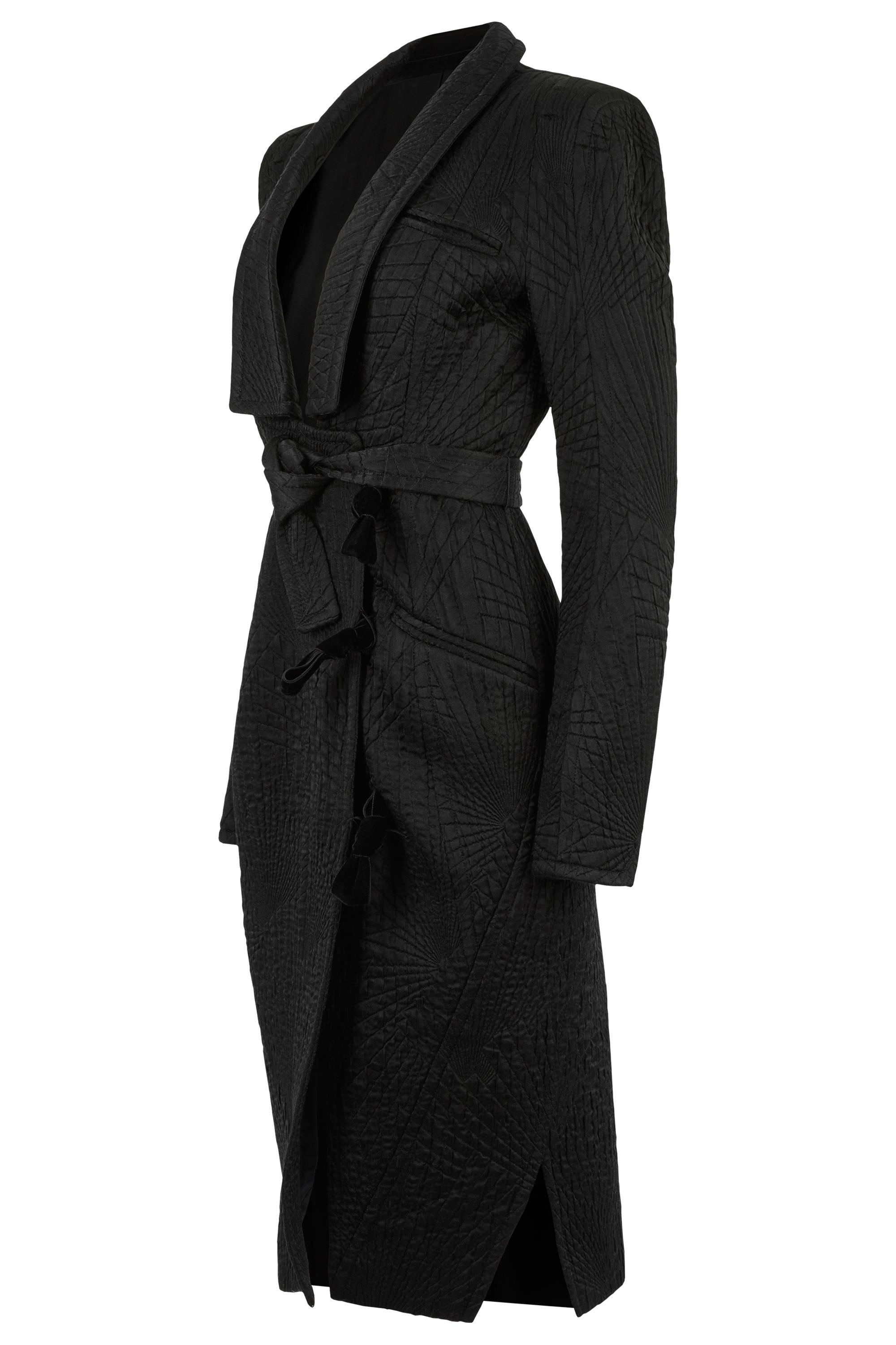 Vintage della collezione Yves Saint Laurent Autunno/Inverno 2004, presenta una vestibilità strutturata longilinea, un jacquard nero scultoreo con una sottile trama trapuntata. Eleganza con cintura auto-legante per definire la vita ed eleganti