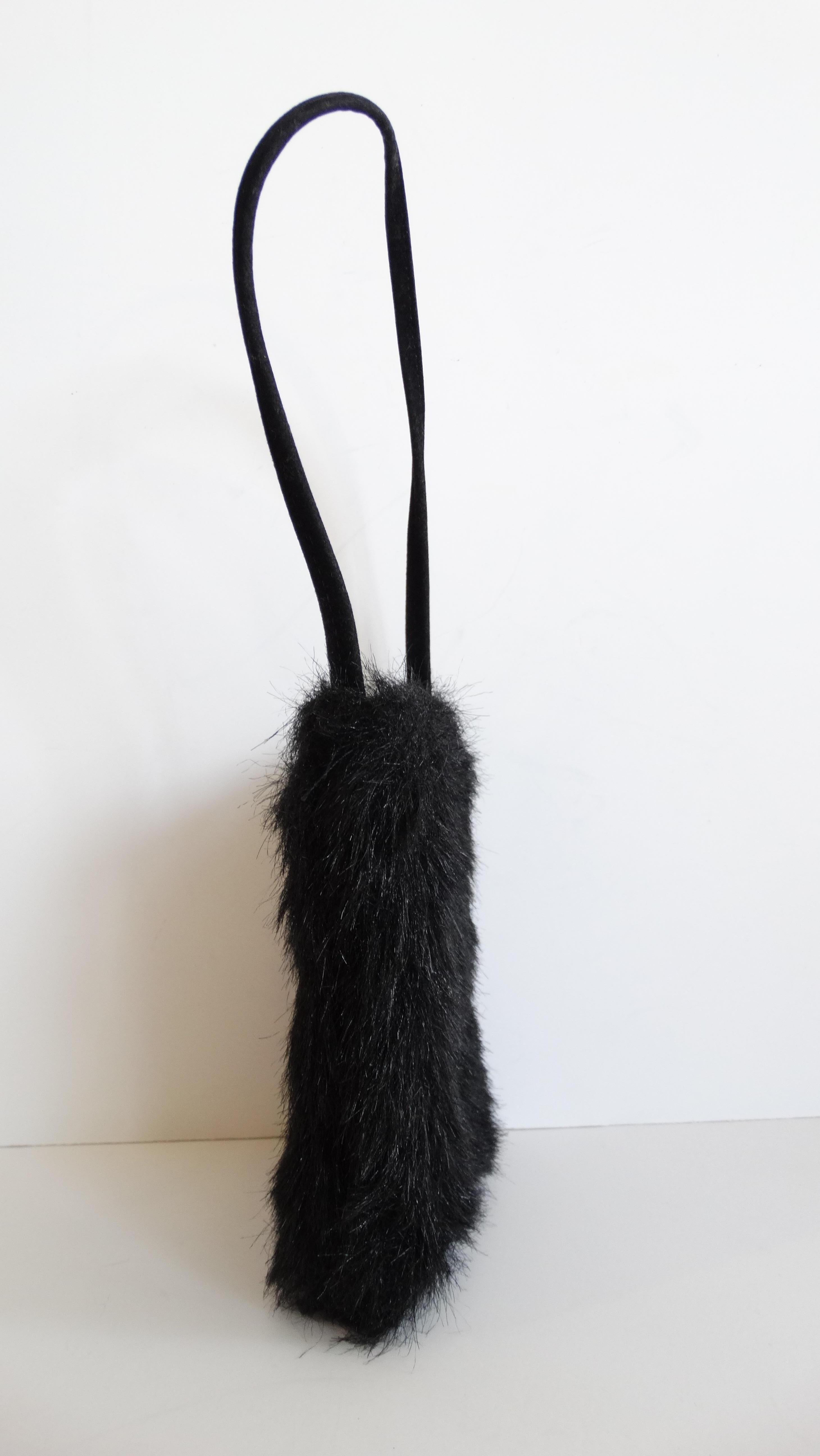 Glamorous vintage fur bag from designer Yves Saint Laurent! Made of a lush black faux fur material and embellished with gold YSL logo charm at the center. Short black fabric top handle with open, tote-like style. Fully lined interior with magnetic