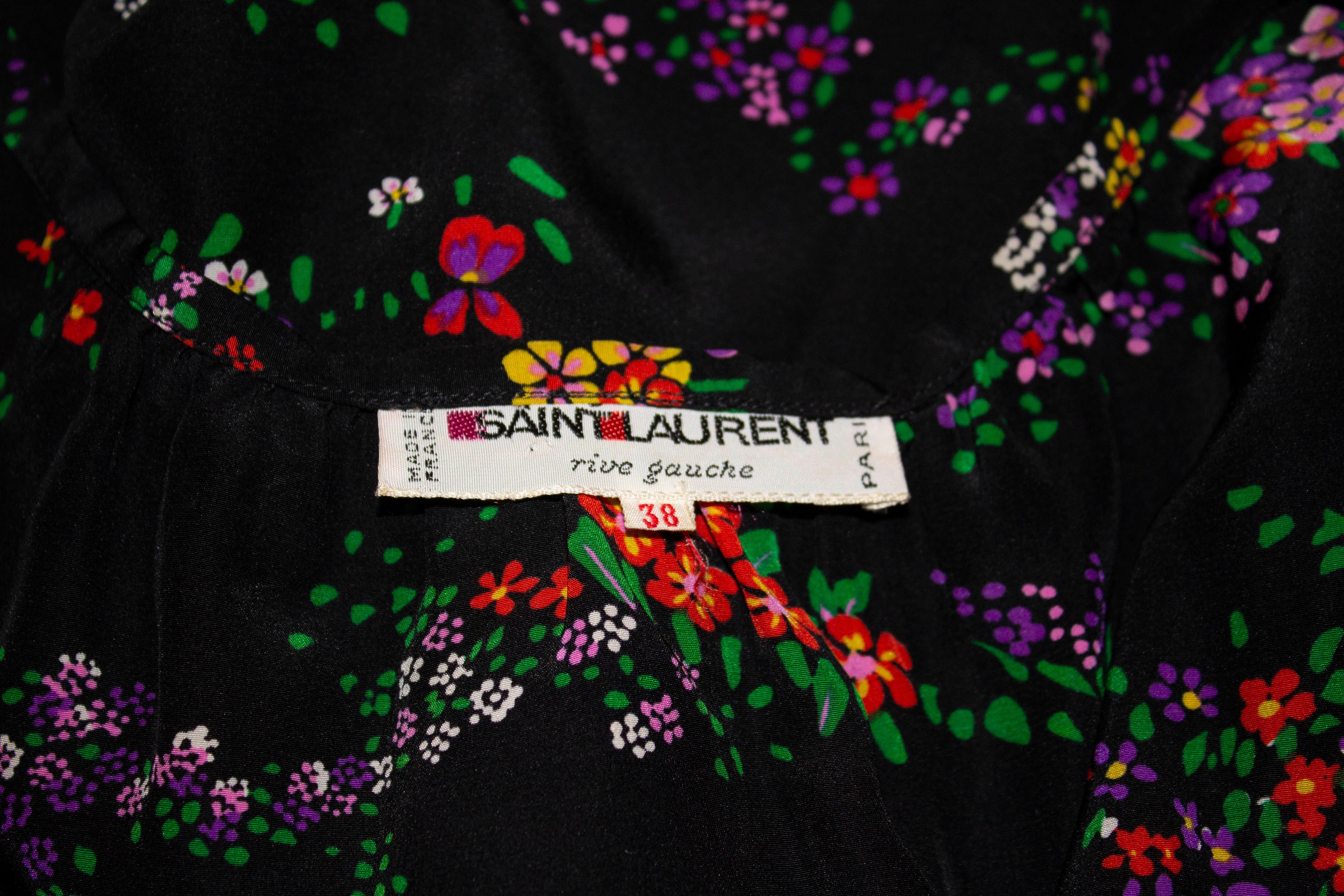A pretty vintage top by Yves Saint Laurent Rive Gauche . The top has a black background with a floral print, and tie neckline and elasticated wrists.  Size 38, it will fit a bust up to 38/39'', length 26''