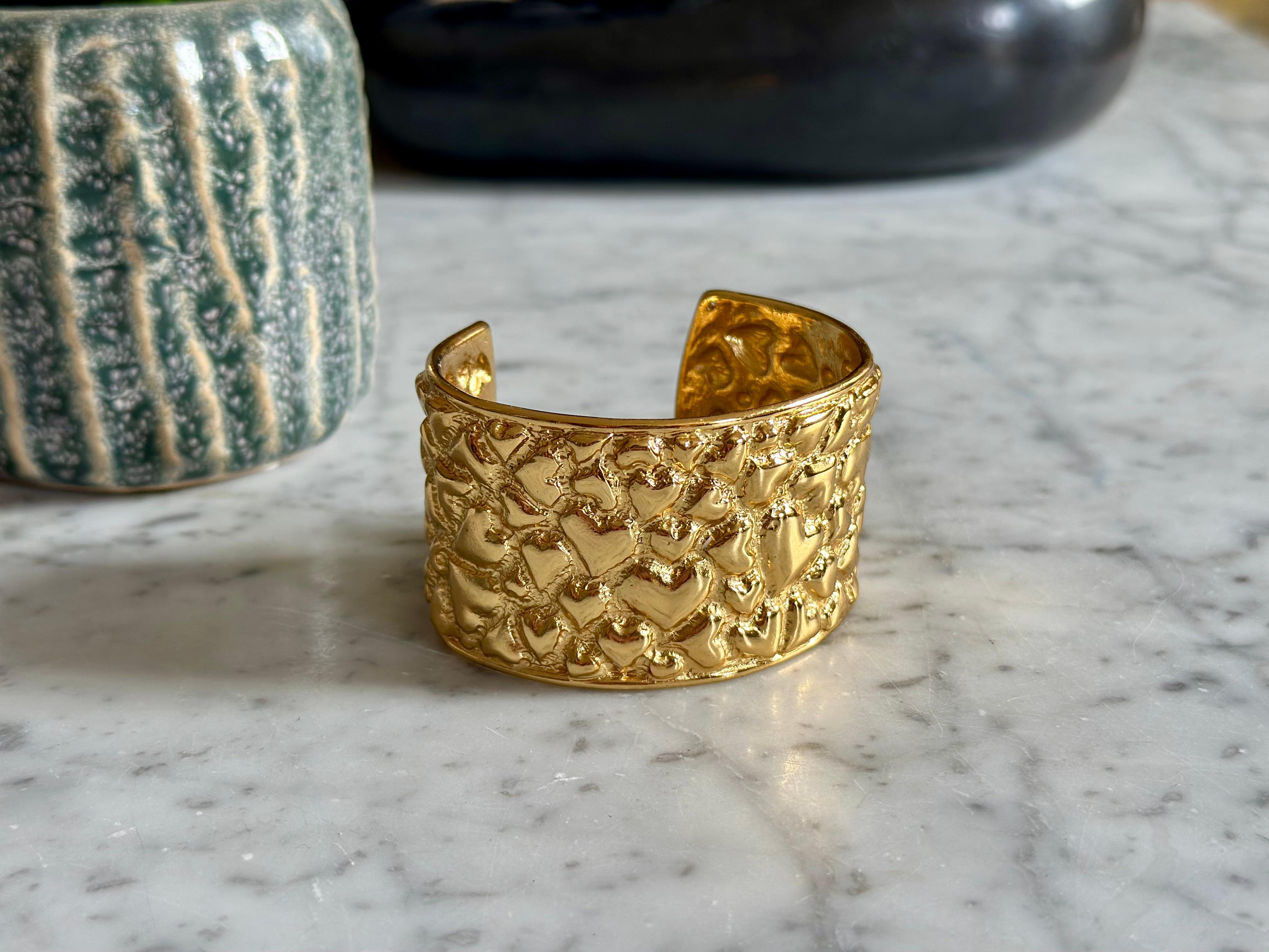 This eye-catching vintage fashion bracelet by Yves Saint Laurent is a true collector’s piece from the bold and glamorous 1980s era. Crafted in France, this wide hammered cuff bracelet is made from gold-toned metal and features a richly textured