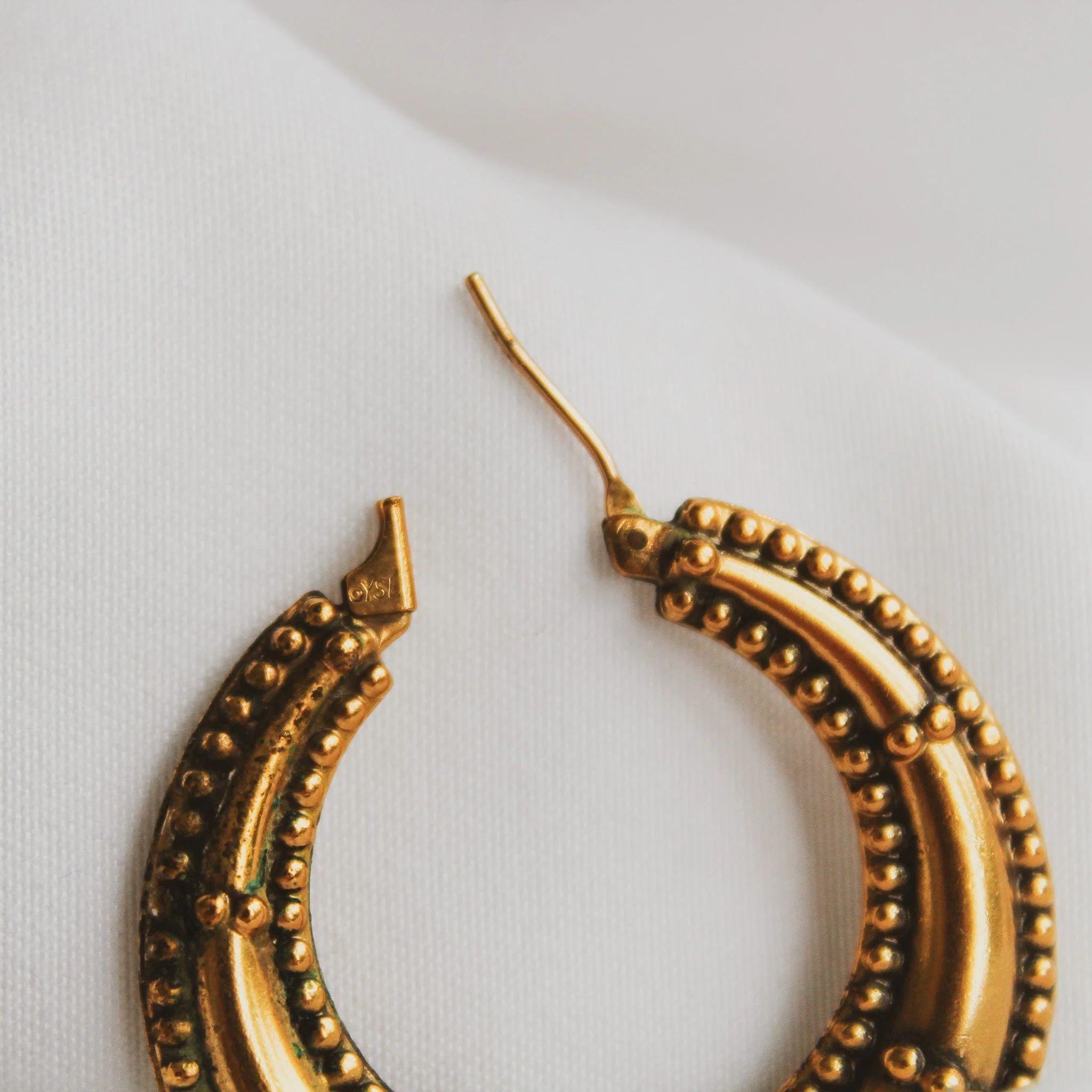 Vintage Yves Saint Laurent 1990s Hoop Earrings for Pierced Ears

Step into the world of vintage fashion with these stunning Yves Saint Laurent 1990s Hoop Earrings. These gold-plated earrings showcase intricate detailing that is sure to turn heads.