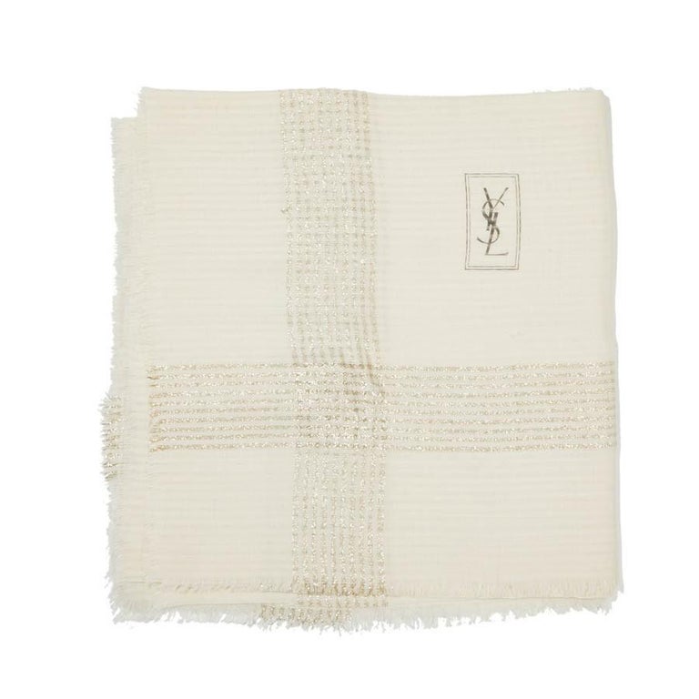 An iconic vintage piece from YSL, the large shawl with lurex threads on a plain off white background. With fringe around the edges and stamped YSL. In very good condition exept a small stain. Note the composition label is not present but it seems to