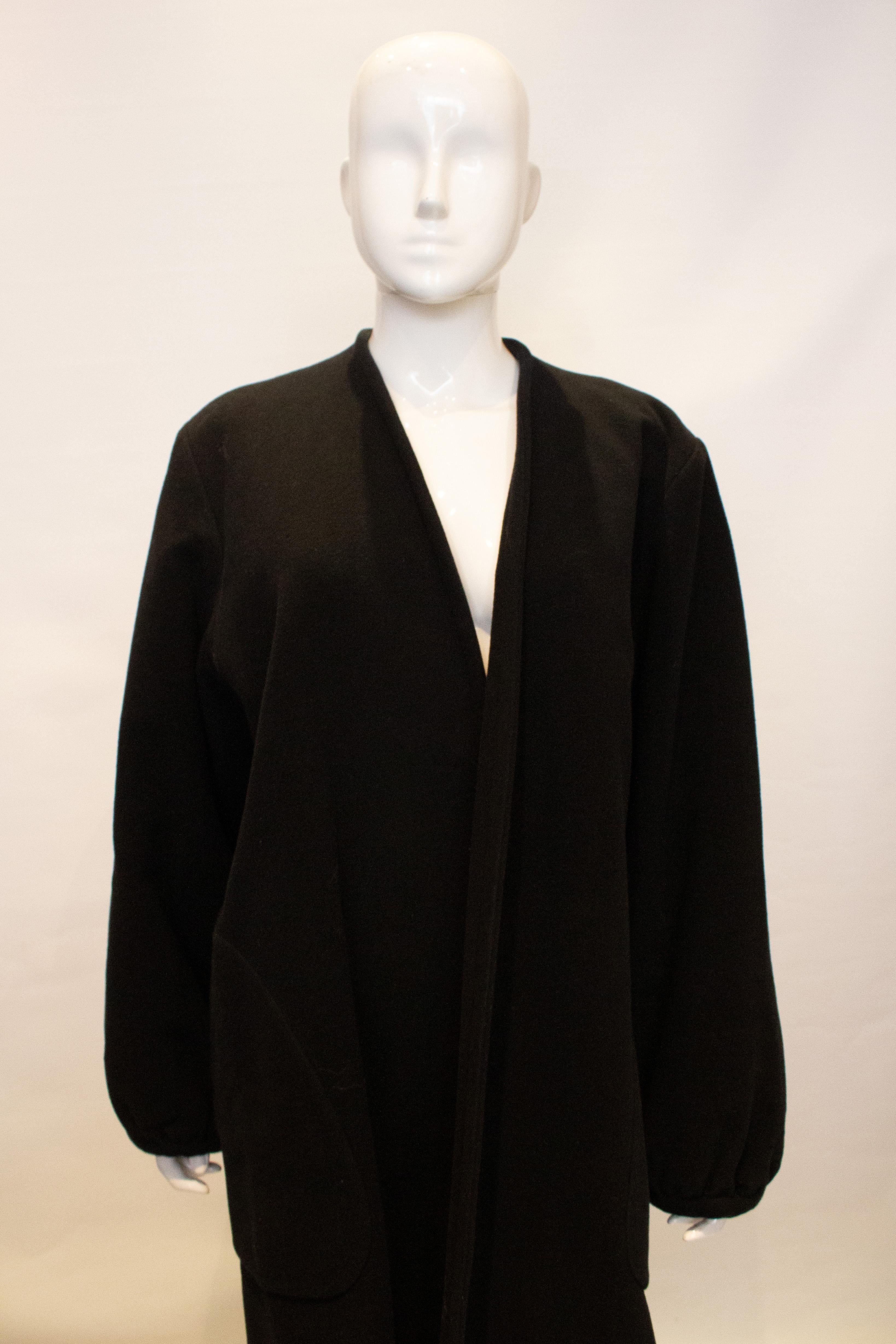 An elegant ad easy to wear black wool coat by Yves Saint Laurent , Rive Gauche, Paris. Label details, H87, H 7177. 100% wool. The coat is collarless, with gathered cuffs and a pocket on either side. The upper part of the coat is lined. Size 36