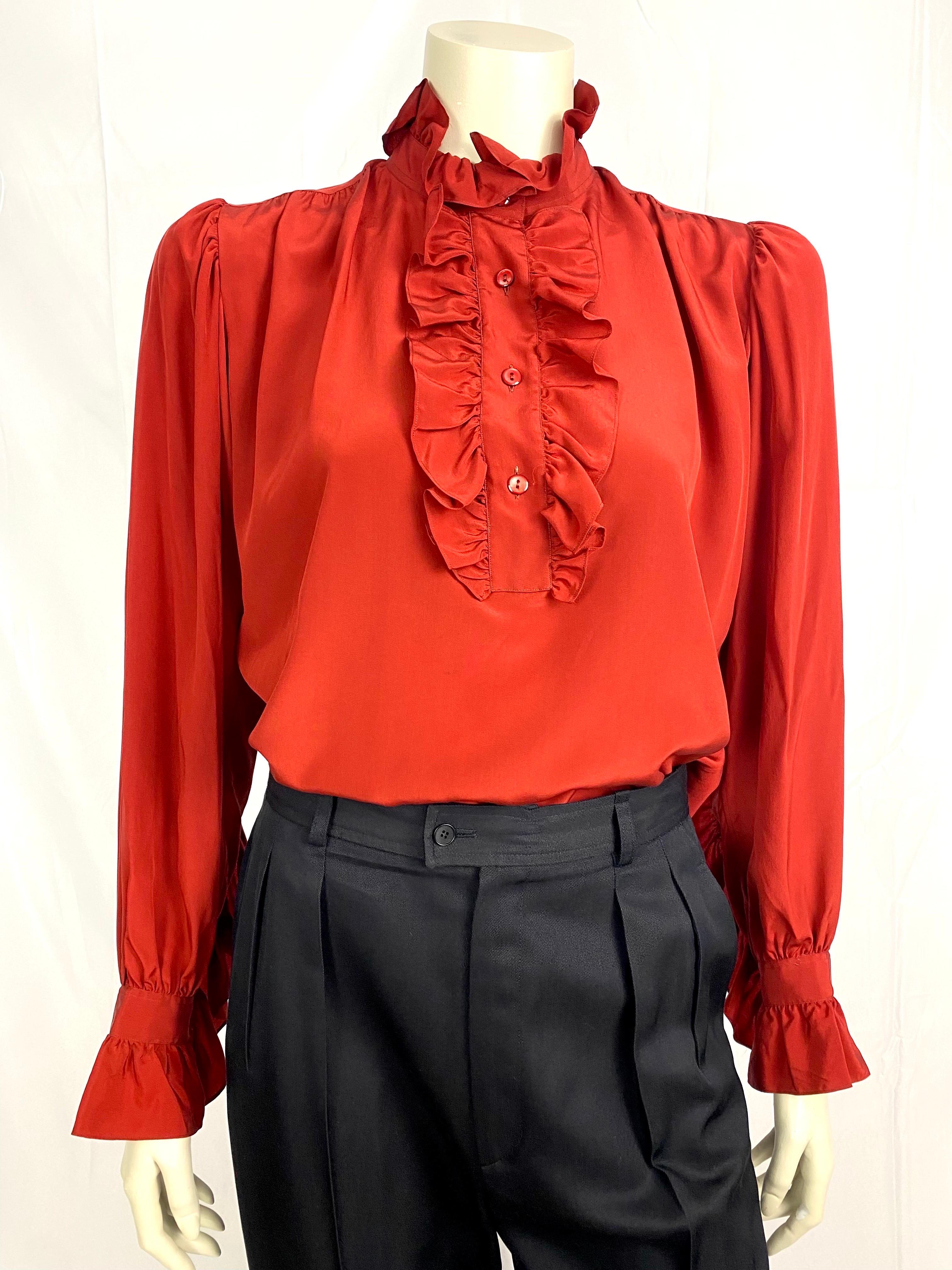 Vintage Yves Saint Laurent Rive Gauche blouse from 1970.
Cardinal red color with a ruffled Pierrot-type collar and a frilly buttoned bib.
Ruffled cuffs that go up slightly on the forearm.
Slightly puffed and gathered sleeves.
The back is also
