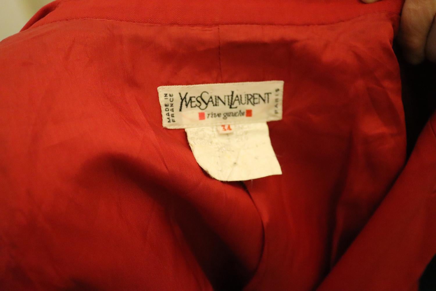Une veste chic en laine rouge vintage Yves Saint Laurent Rive Gauche. La veste dispose d'une poche poitrine et de deux poches sur les hanches.  Elle possède un col coupé, les épaulettes d'origine et tous les boutons d'origine. Date 1992, Taille 34