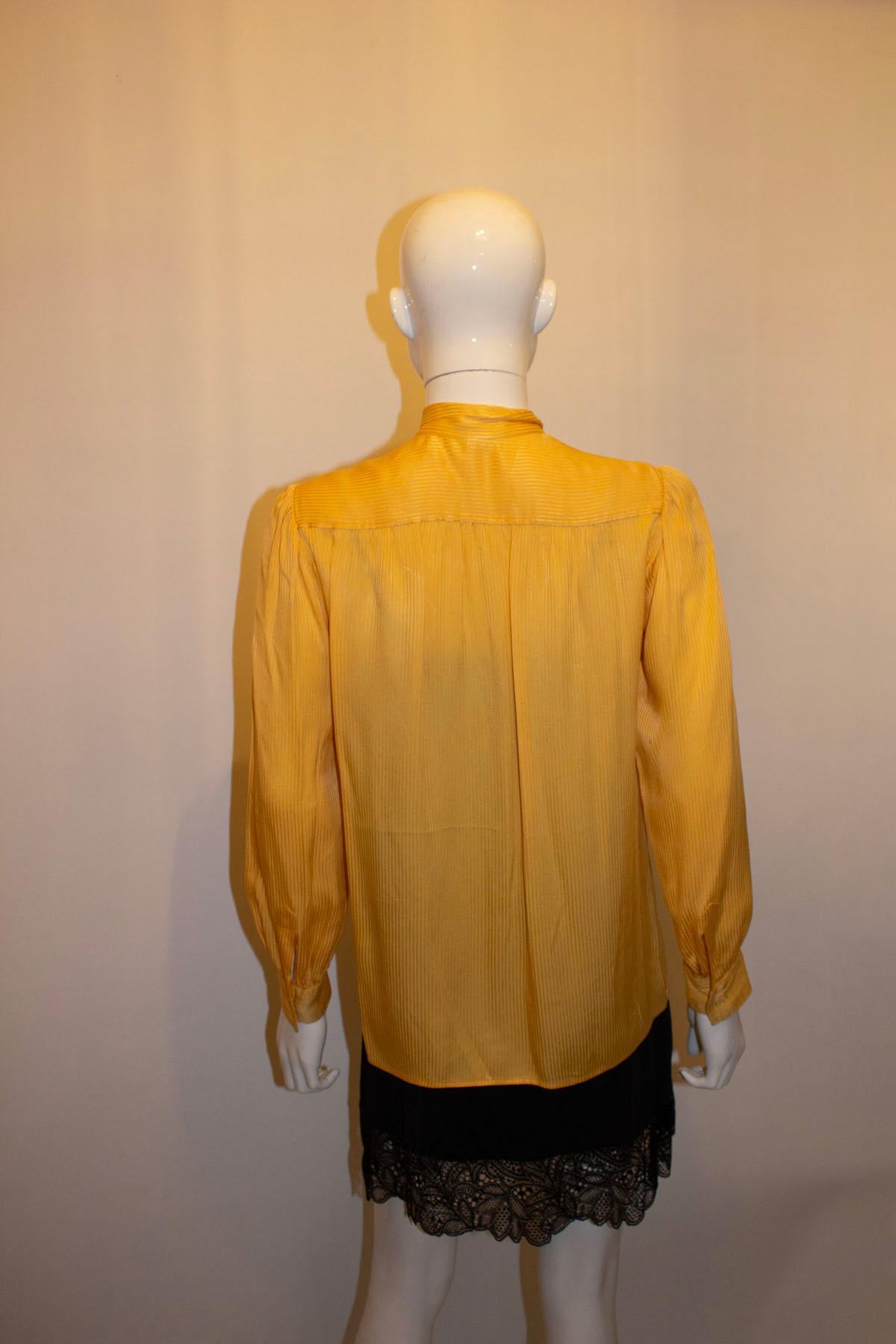 A super vintage silk blouse by Yves Saint Laurent Rive Gauche.  In a sunny yellow colour, the blouse has a single button fastening at the neck, a pussy bow tie single button cuffs and gathering a the yoke, front and back. 
Size 34 Measurements :