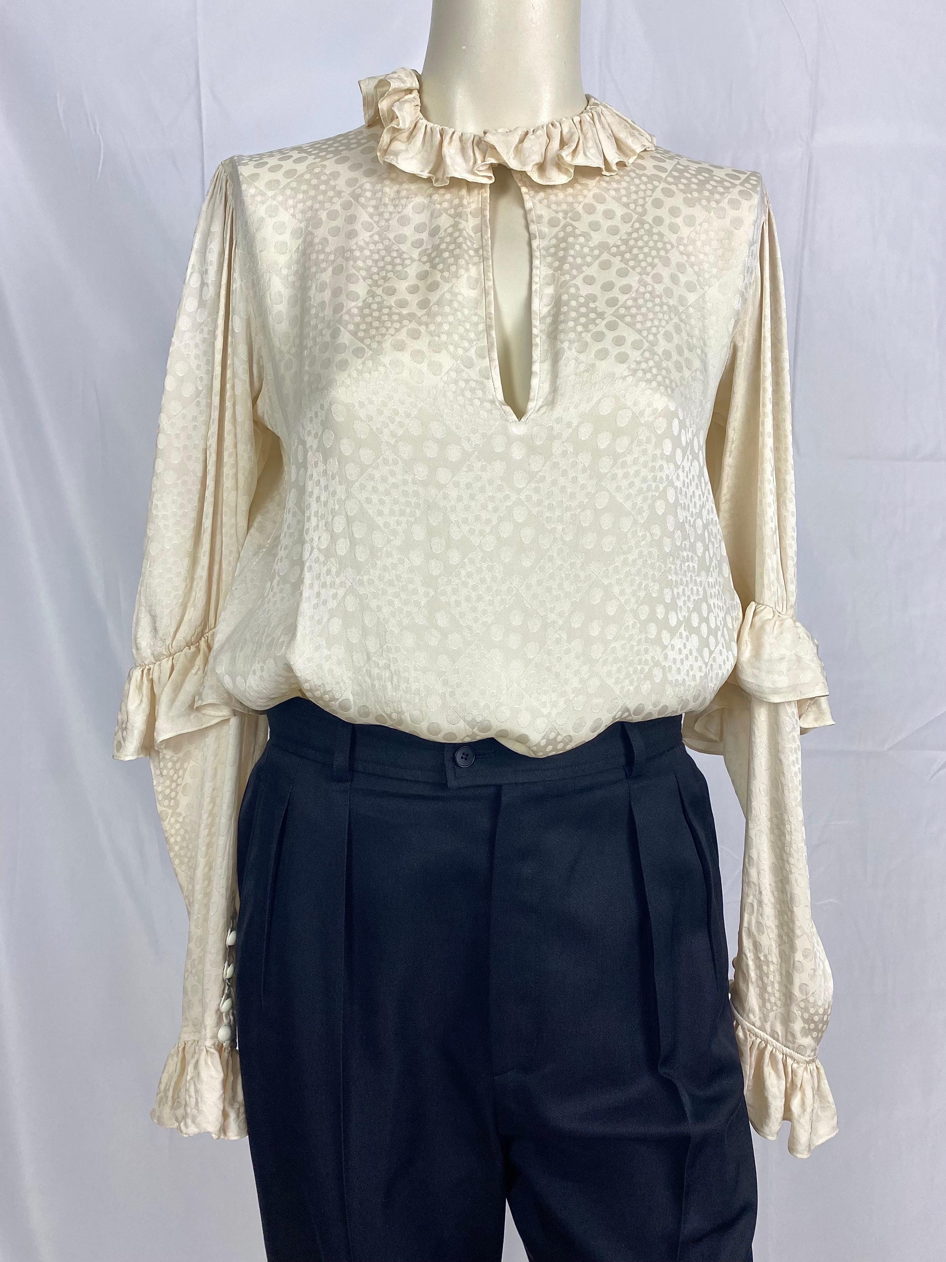 Vintage Yves Saint Laurent Rive gauche blouse inSilk from 1970, tone-on-tone beaded patterns, pretty Pierrot-style ruffled collar closing with a small round button.
Ruffles at elbows and wrists.
4 buttons close the sleeves of the blouse.
Size