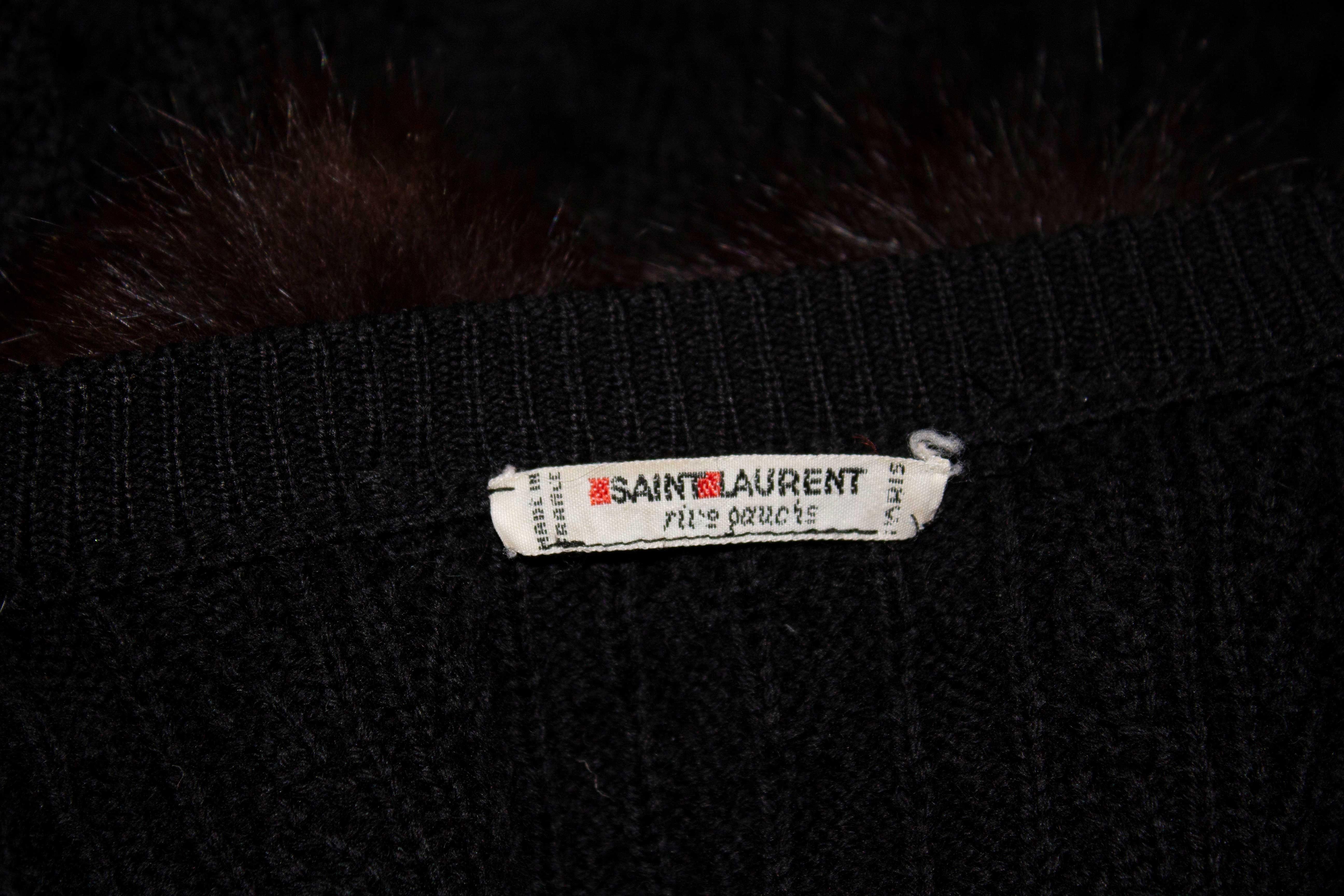 A wonderful warmer for Fall. This black wool knitted cardigan by Yves Satin Laurent Rive Gauche has a pocket either side at hip level, a button front opening and small knitted shoulder pads. It has mink ball decoration around the neckline. Size 44 .