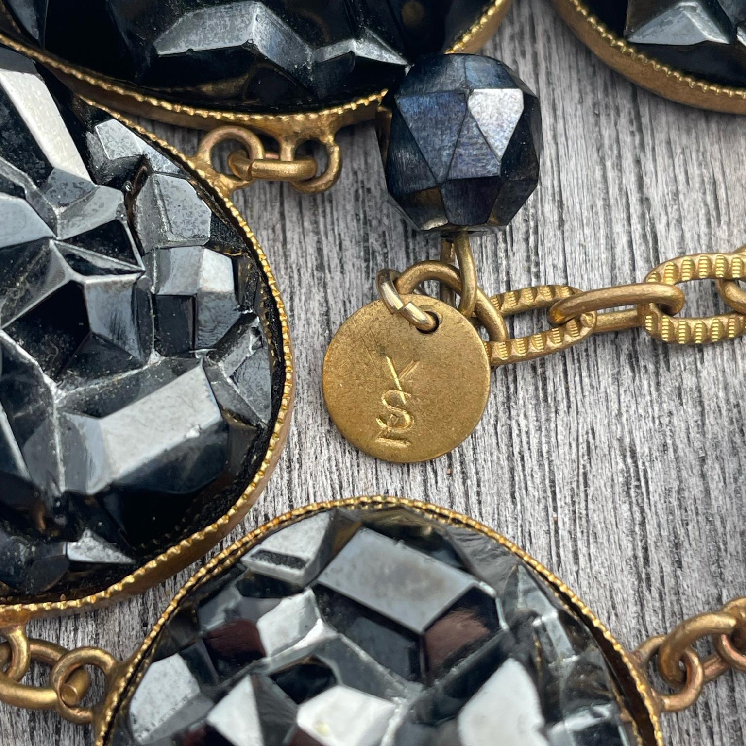 This is one of the most unique vintage Yves Saint Laurent vintage jewelry pieces we've come across! This 1980's limited edition necklace looks like chunky pieces of broken dark gunmetal grey geodes on gold plated ovals. We have seen similar style
