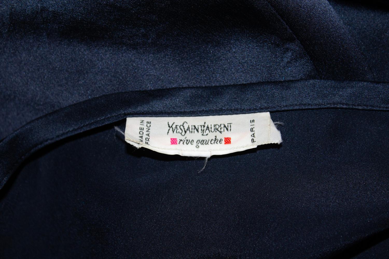 Una splendida camicetta vintage in seta di Yves Saint Laurent Rive Gauche.  La blusa è realizzata in morbidissima seta e presenta un dettaglio a balze sui polsini e sul davanti. Ha i pad originali (che possono essere rimossi) e meravigliosi bottoni.