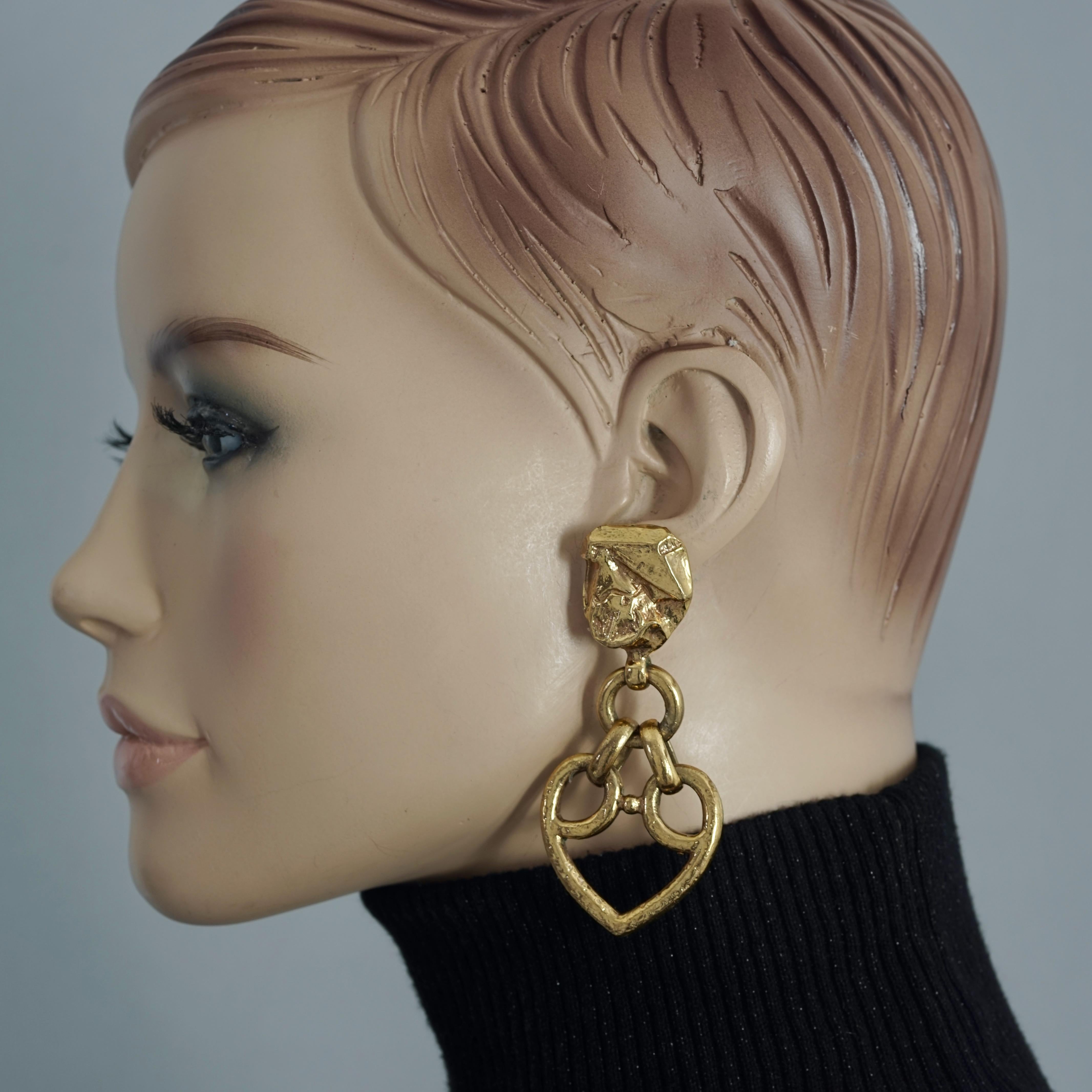 Vintage YVES SAINT LAURENT Textured Heart Drop Earrings

Measurements:
Height: 3 inches
Width: 1 3/8 inches

Features:
- 100% Authentic YVES SAINT LAURENT.
- Chunky textured top part.
- Dangling open work heart pendant.
- Clip back earrings.
-