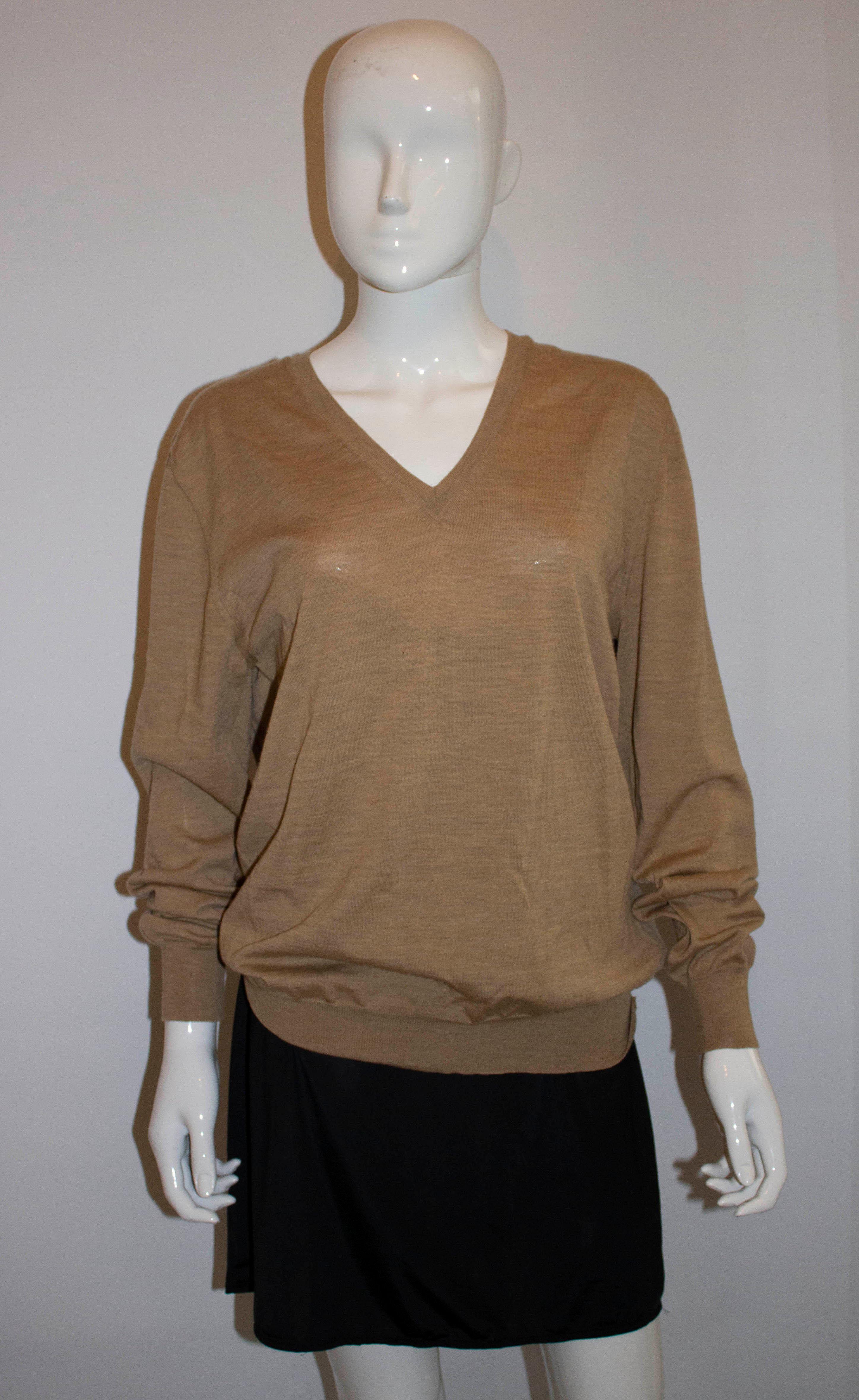 A chic vintage jumper by Yves Saint Laurent. In a pretty biscuit colour the jumper has ribbon detail on the shoulder, interesting detail on the seams and YSL cut out on the front.  100% wool
Size XL Bust up to 44'', length 27''