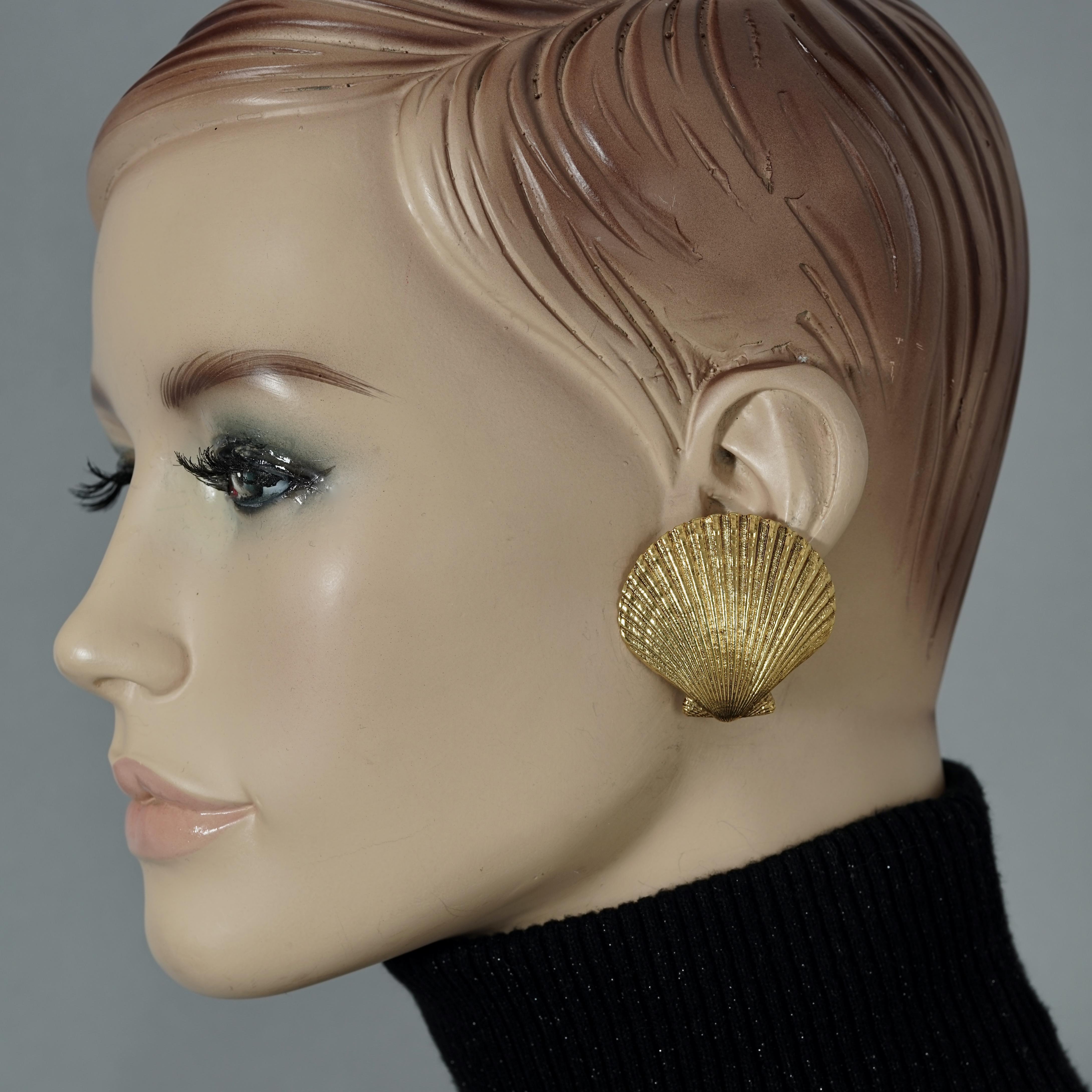 Vintage YVES SAINT LAURENT Ysl Clam Shell Earrings

Measurements:
Height: 1.57 inches (4 cm)
Width: 1.57 inches (4 cm)
Weight per Earring: 13 grams

Features:
- 100% Authentic YVES SAINT LAURENT.
- Textured clam shell shape earrings.
- Gold tone.
-