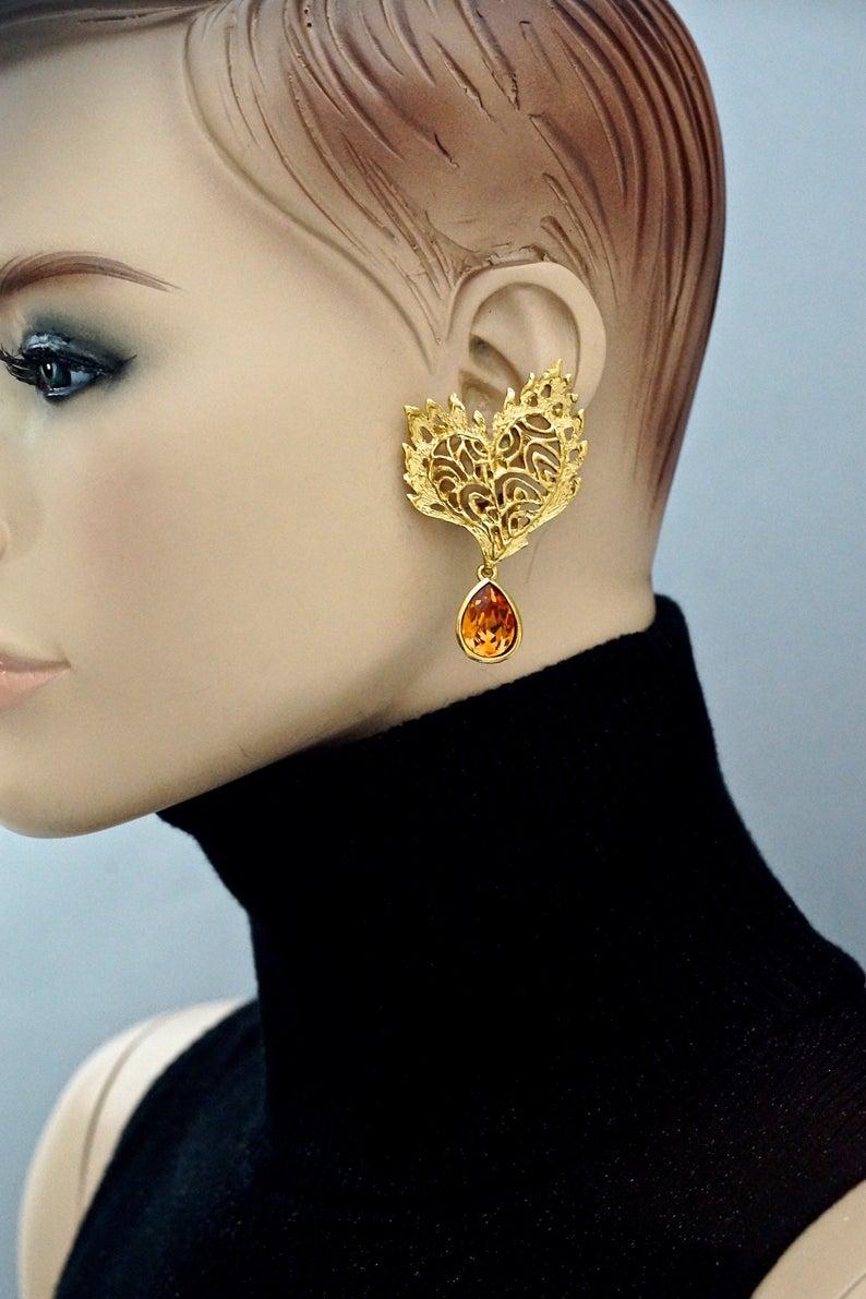 Vintage YVES SAINT LAURENT Ysl Heart Lace Amber Dangling Earrings

Measurements:
Height: 2.44 inches (6.2 cm)
Width: 1.57 inches (4 cm)
Weight: 14 grams

Features:
- 100% Authentic YVES SAINT LAURENT.
- Heart lace pattern earrings with amber drop