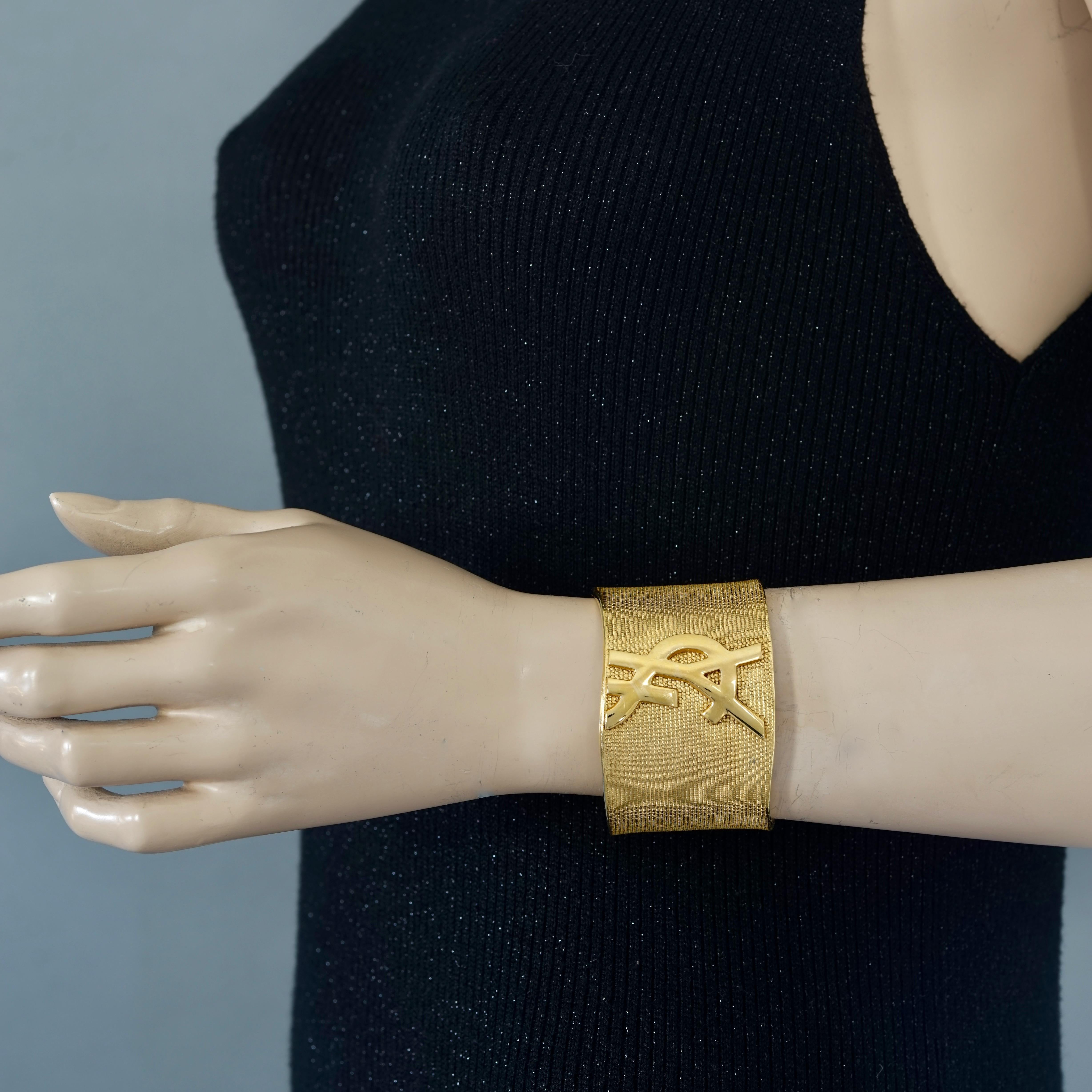 Vintage YVES SAINT LAURENT Ysl Logo Asymmetric Cuff Bracelet

Measurements:
Height: 1.61 inches (4.1 cm)
Inner Circumference: 7 inches (17.8 cm) including the opening

Features:
- 100% Authentic YVES SAINT LAURENT.
- Textured ribbed cuff.
- Raised