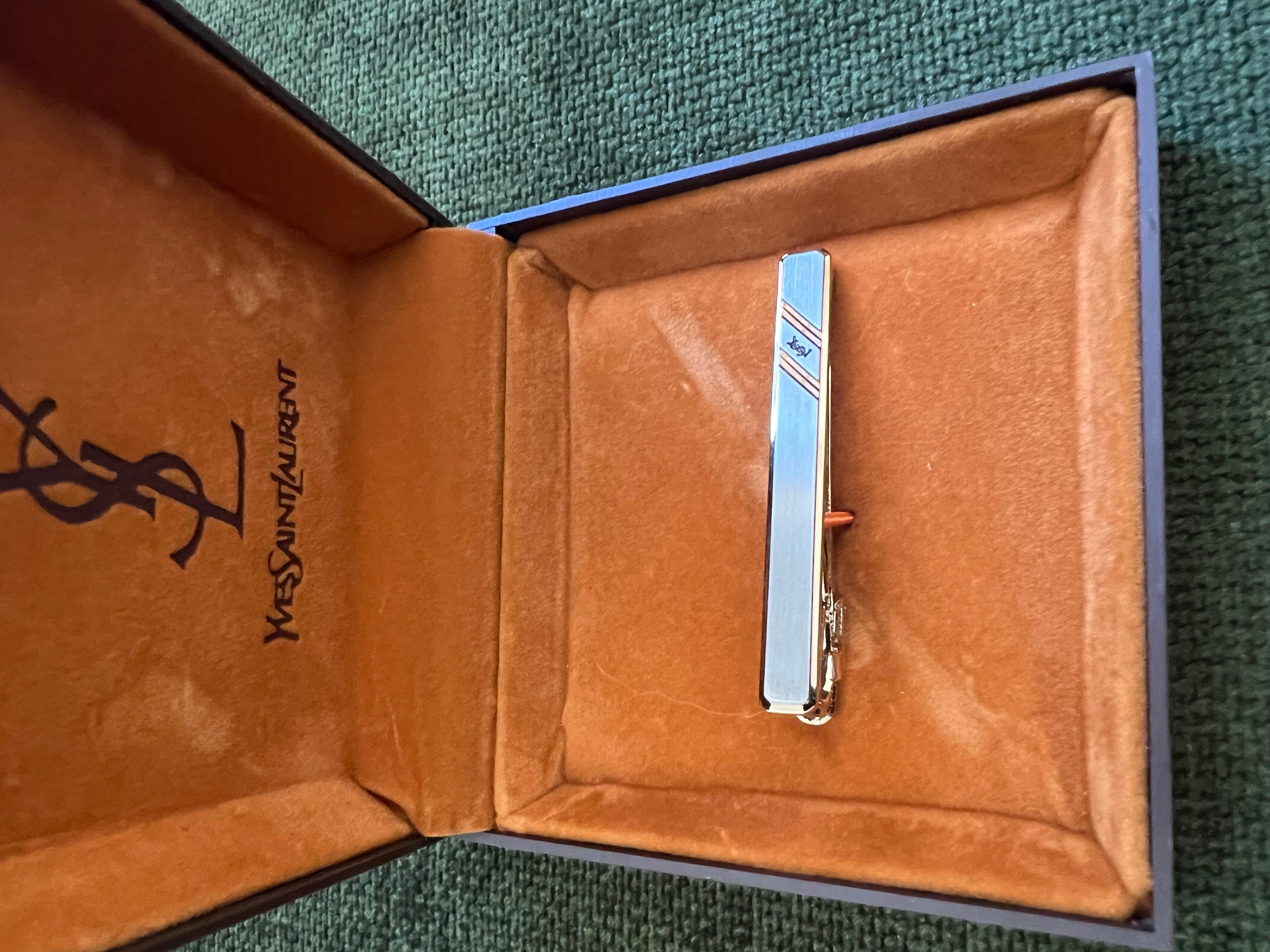 Vintage Yves Saint Laurent YSL Logo Krawattenklammer Original Etui Goldplatte und Edelstahl Krawattenklammer mit Dior-Logo auf der Vorderseite, in Original YSL Schokolade Wildleder Etui. 
Circa 1990er Jahre 
In fantastischem Zustand
Retro, schick