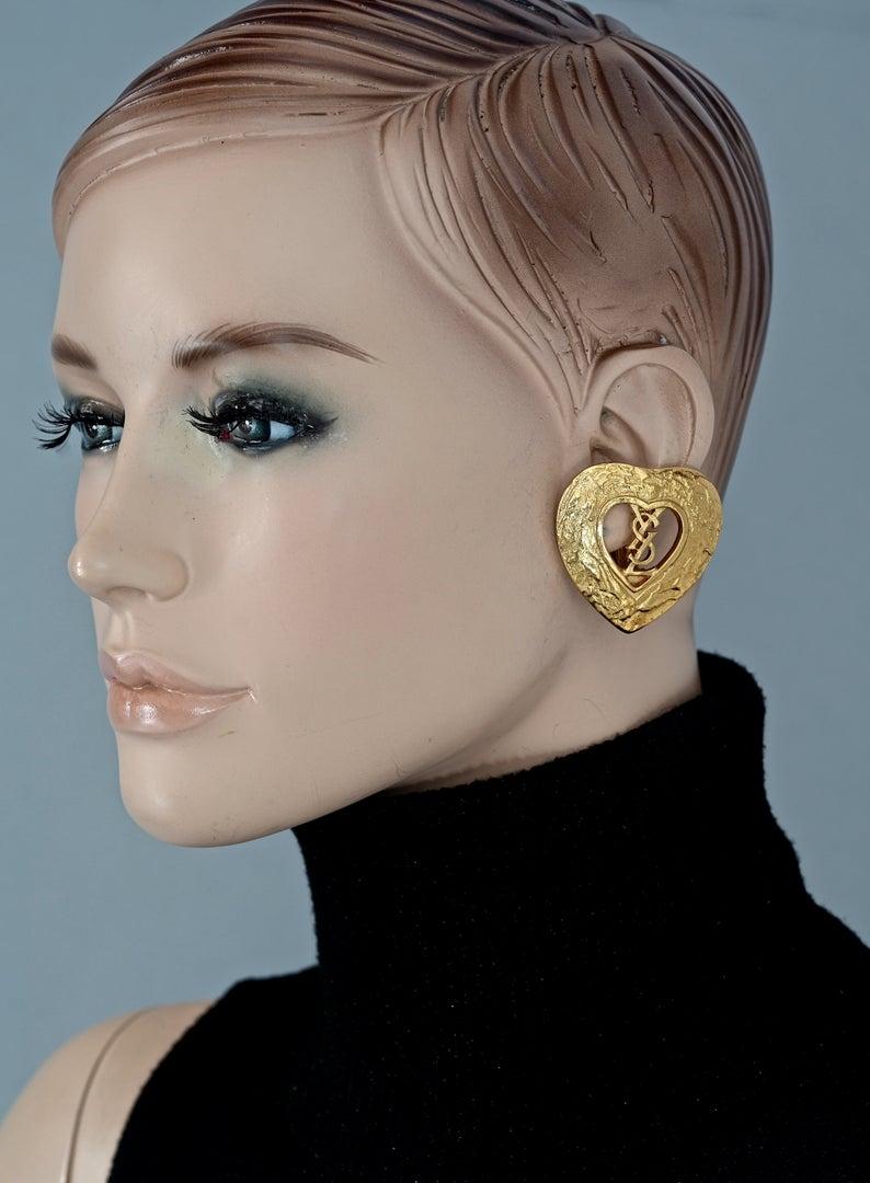 Vintage YVES SAINT LAURENT Ysl Logo Heart Openwork Earrings

Measurements:
Height: 1.57 inches (4 cm)
Width: 1.57 inches (4 cm)
Weight per Earring: 16 grams

Features:
- 100% Authentic YVES SAINT LAURENT.
- Textured heart openwork earrings with YSL