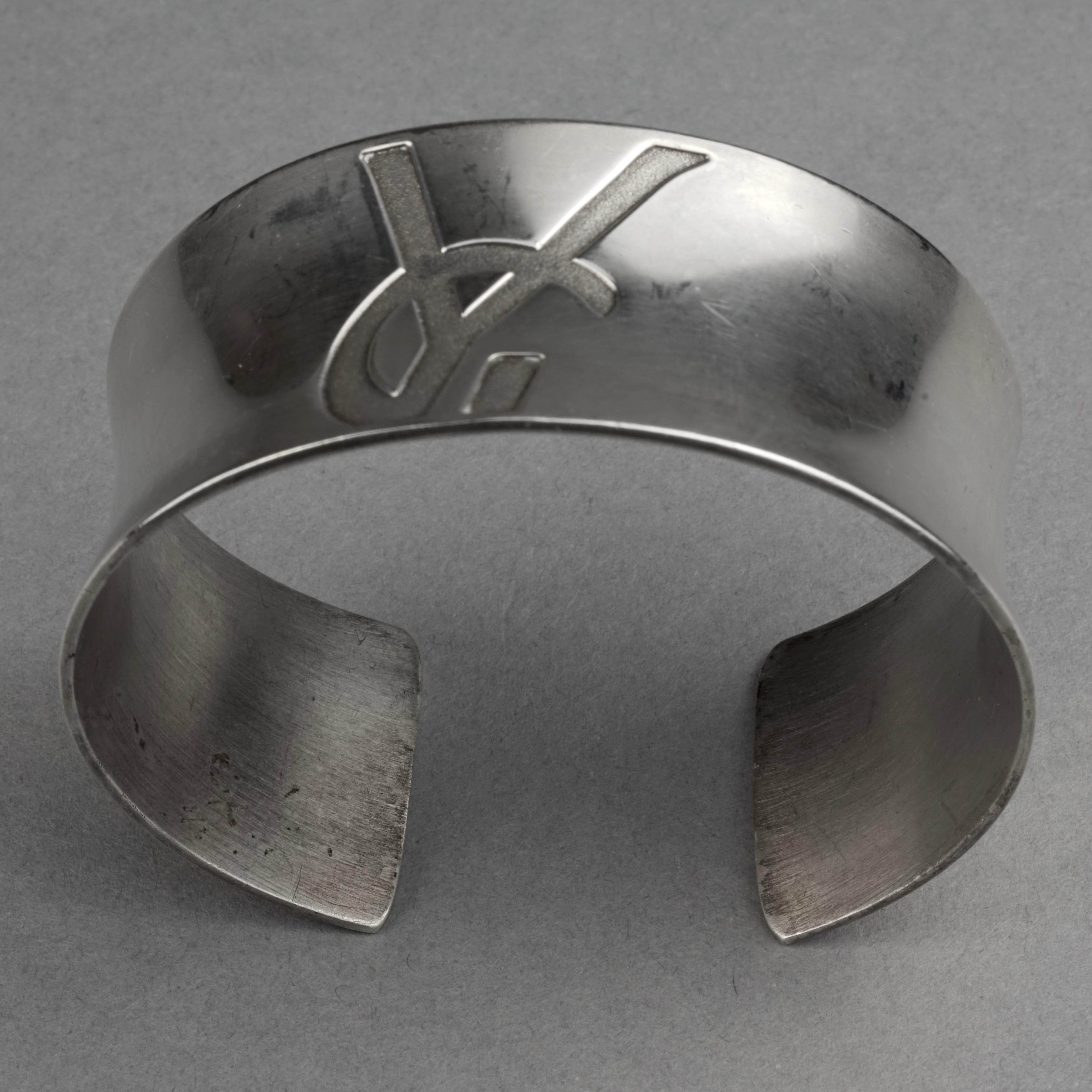 Vintage YVES SAINT LAURENT Ysl Logo Sterling Silver Cuff Bracelet

Measurements:
Height: 1.06 inches (2.7 cm)
Circumference: 6.50 inches (16.5 cm)

Features:
- 100% Authentic YVES SAINT LAURENT.
- Sterling silver cuff bracelet with engraved YSL logo