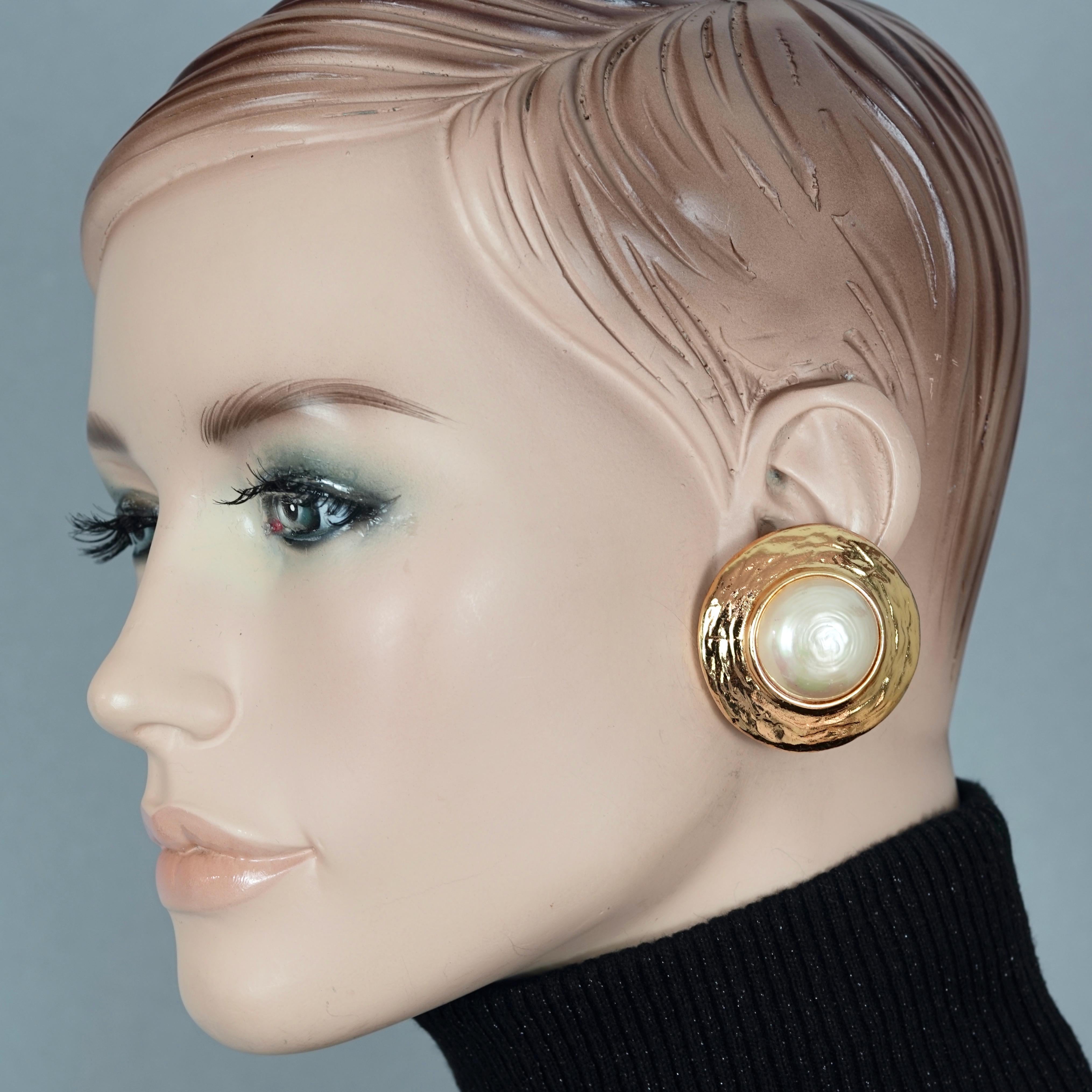 Vintage YVES SAINT LAURENT Ysl Pearl Textured Disc Earrings

Measurements:
Height: 1.61 inches (4.1 cm)
Width: 1.61 inches (4.1 cm)
Weight per Earring: 28 grams

Features:
- 100% Authentic YVES SAINT LAURENT.
- Textured discs with pearl at the