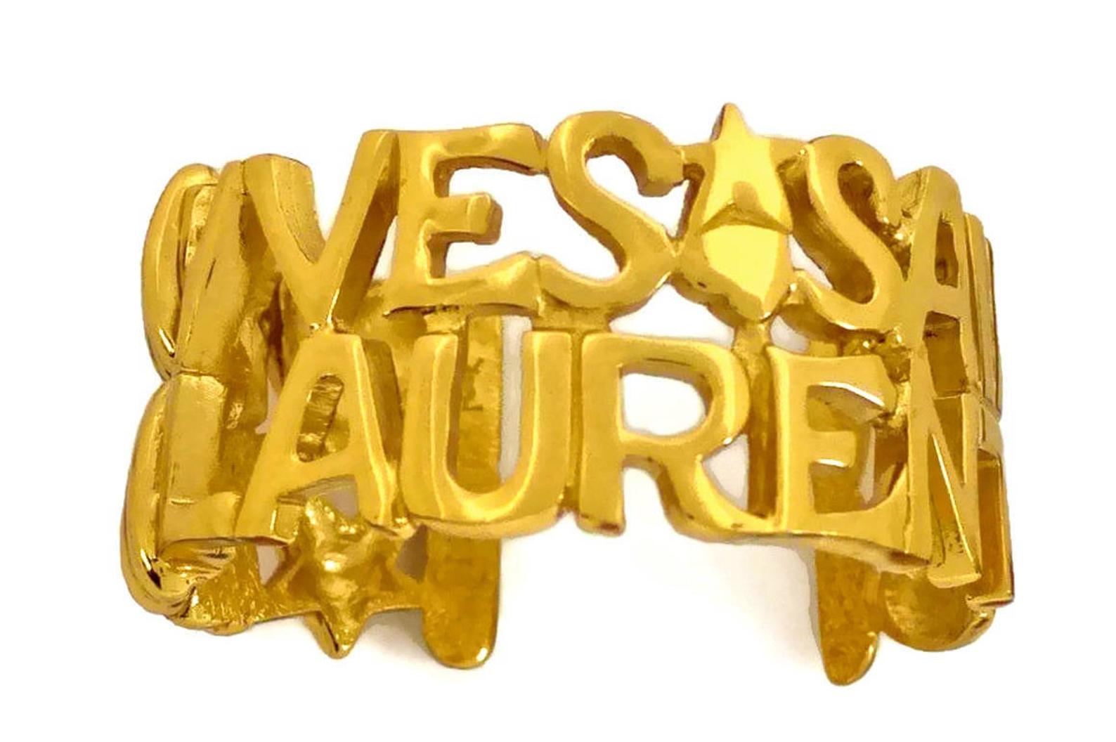 Vintage YVES SAINT LAURENT Ysl Spelled Letter Bracelet Cuff

Measurement:
Height: 1.33 inches (3.4 cms)
Circumference: 6.29 inches (16 cm)

Features:
- 100% Authentic YVES SAINT LAURENT.
- Yves Saint Laurent spelled in chunky letters with hearts and