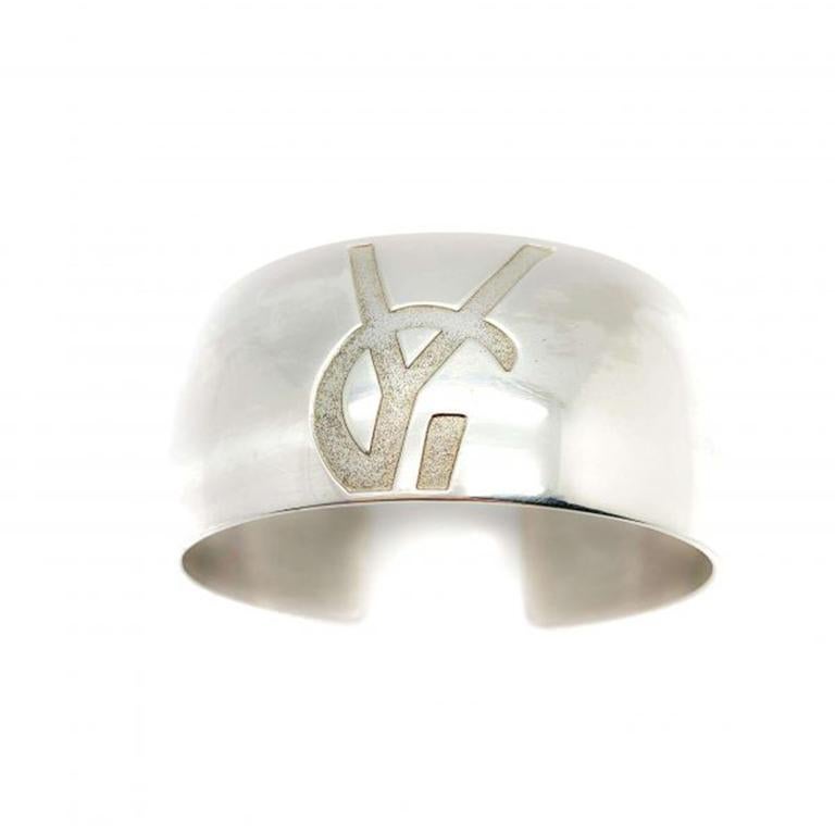 What a rare and fabulous French designer cuff. A vintage Yves Saint Laurent Sterling Bangle. Featuring solid sterling silver in a broad contemporary style band engraved with the iconic YSL logo. This cuff is seriously high quality, made in a weighty