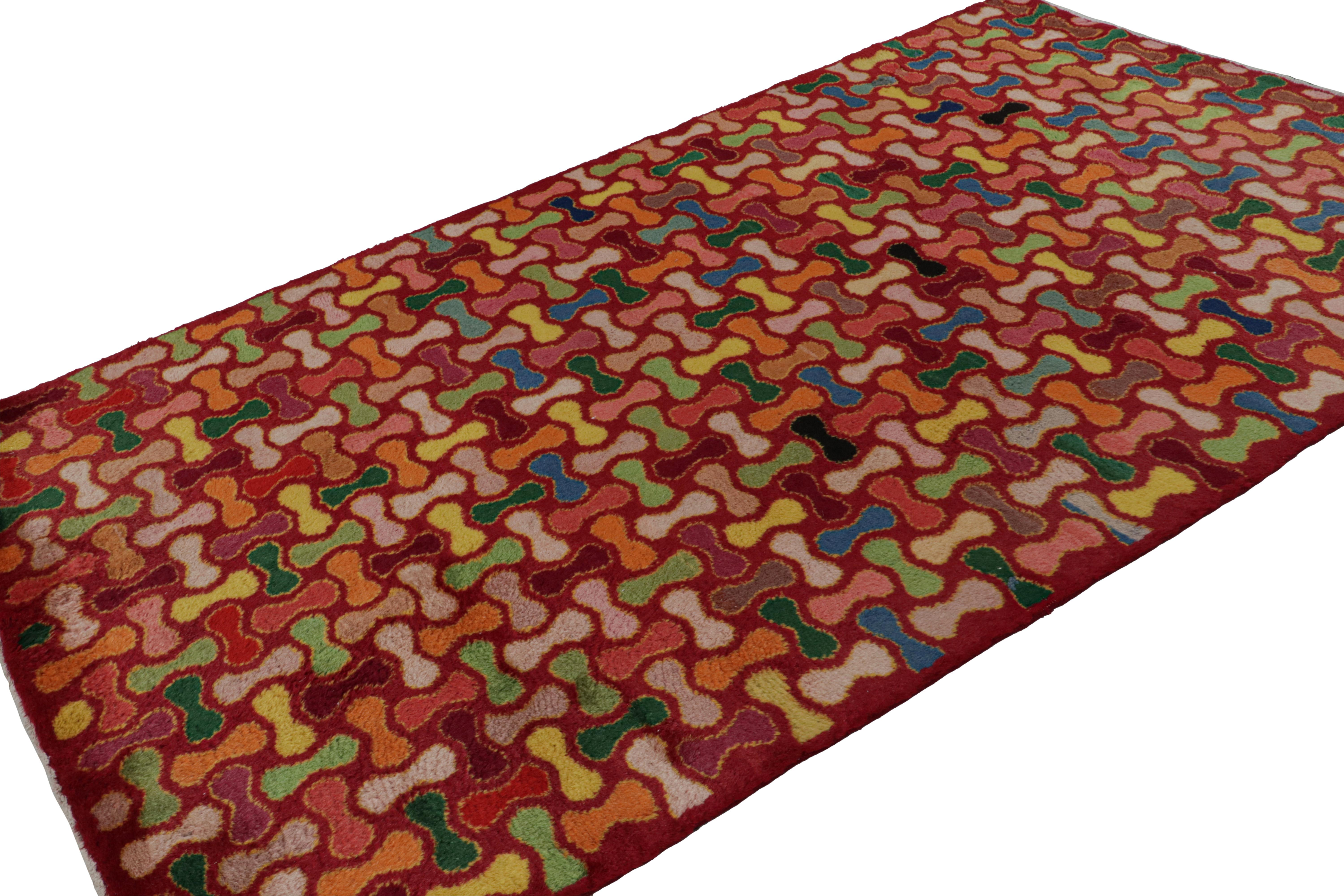 Hand-knotted in wool, circa 1960 - 1970, this 5x9 vintage Müren Art Deco rug features a unique polychromatic geometric design on a rich red field. This is a quintessential Müren piece for its playful sense of movement, choices of color and the rare