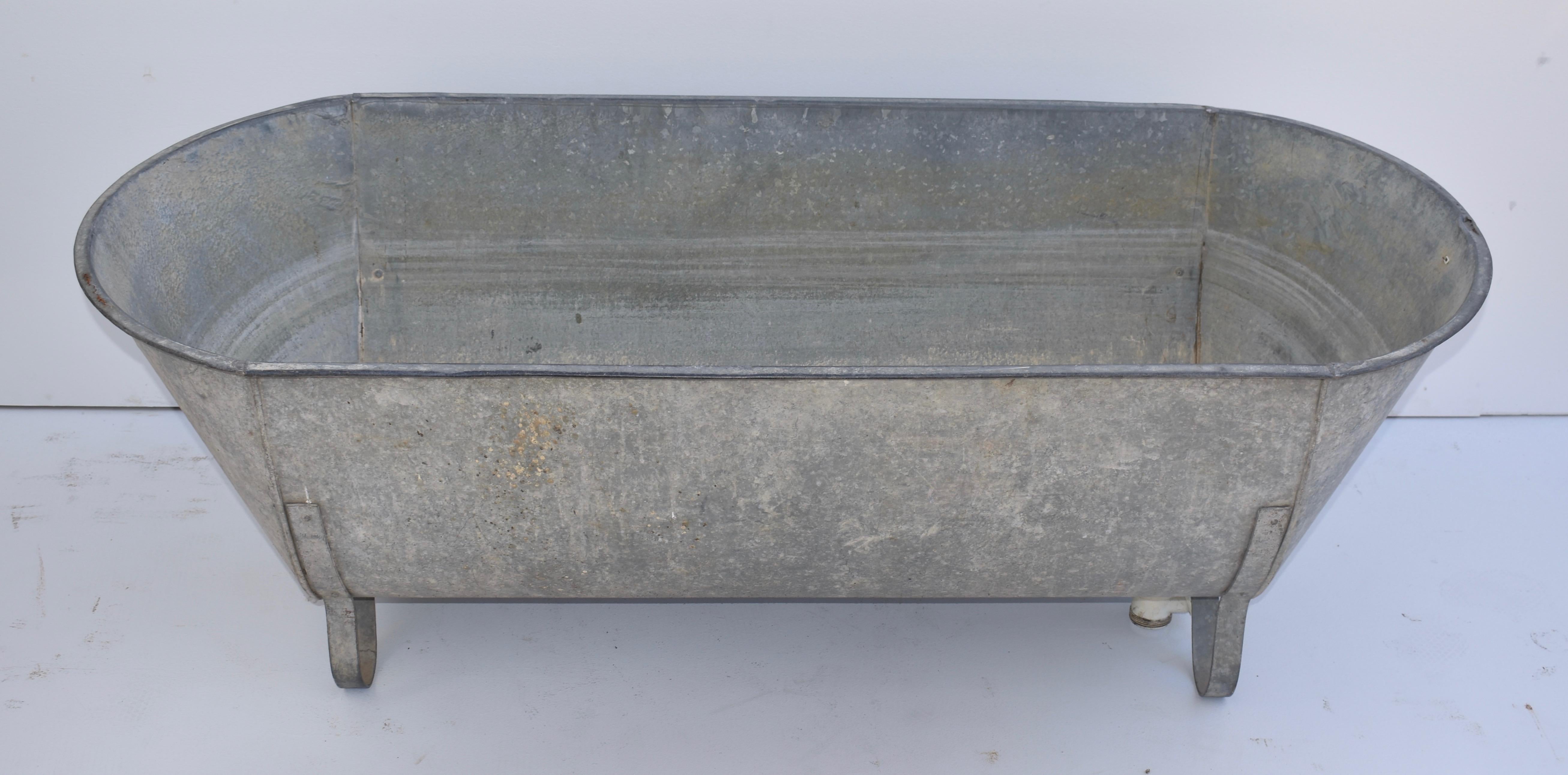 This is a Central European zinc bathtub with attractive curled iron feet. It has a retro-fitted plastic trap and drain hole liner.