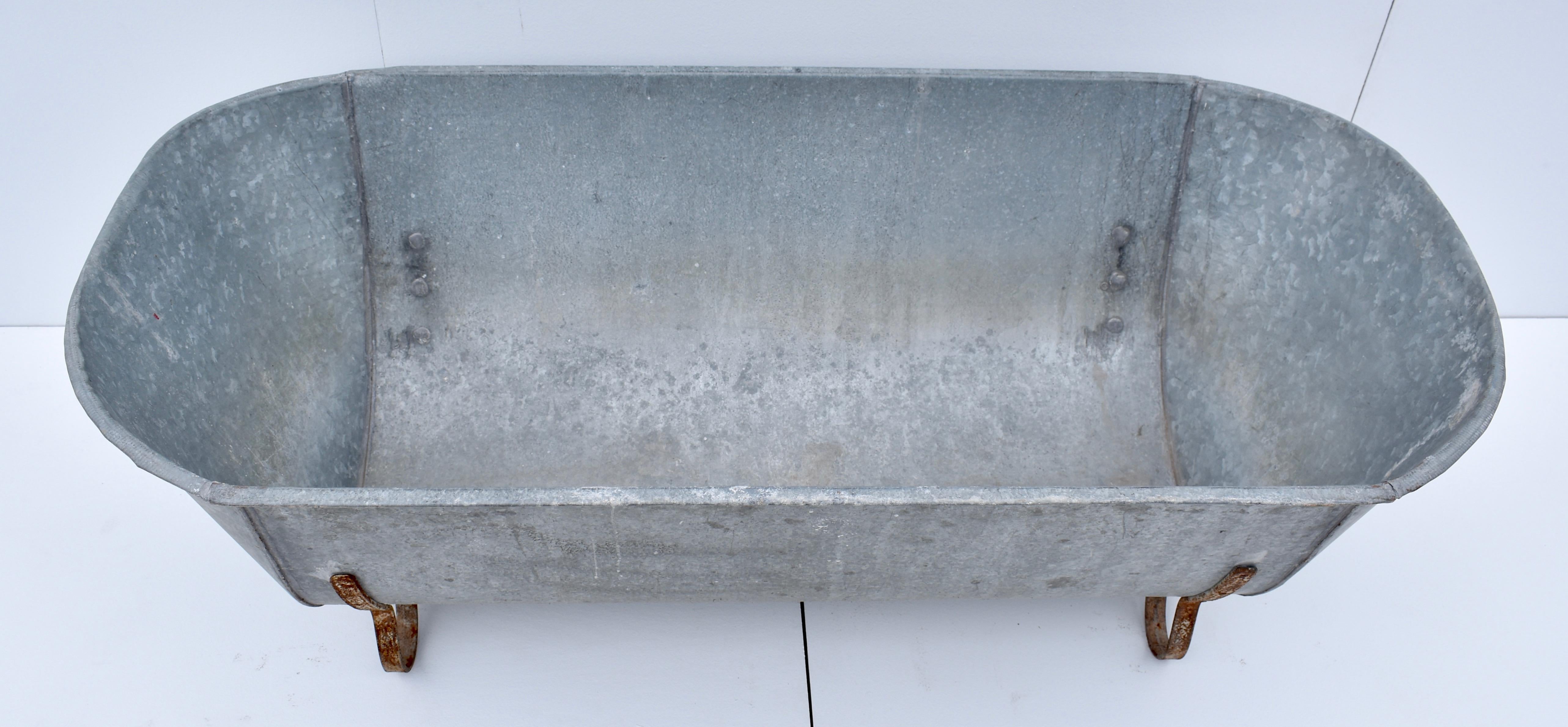 This is a vintage Central European zinc bathtub with attractive curled iron feet. There is no drain hole, but a retrofit may be possible. In good watertight condition.