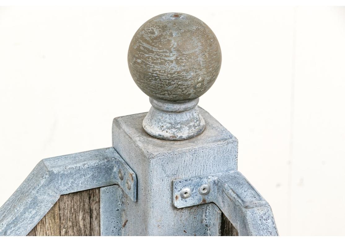 Jardinera grande con armazón de cinc perfilado, lados altos incurvados, aletas de bola y elevada sobre pies perfilados. Los laterales rellenos de paneles de teca maciza. La base es un marco en X abierto. 

Dimensiones; 41 1/2