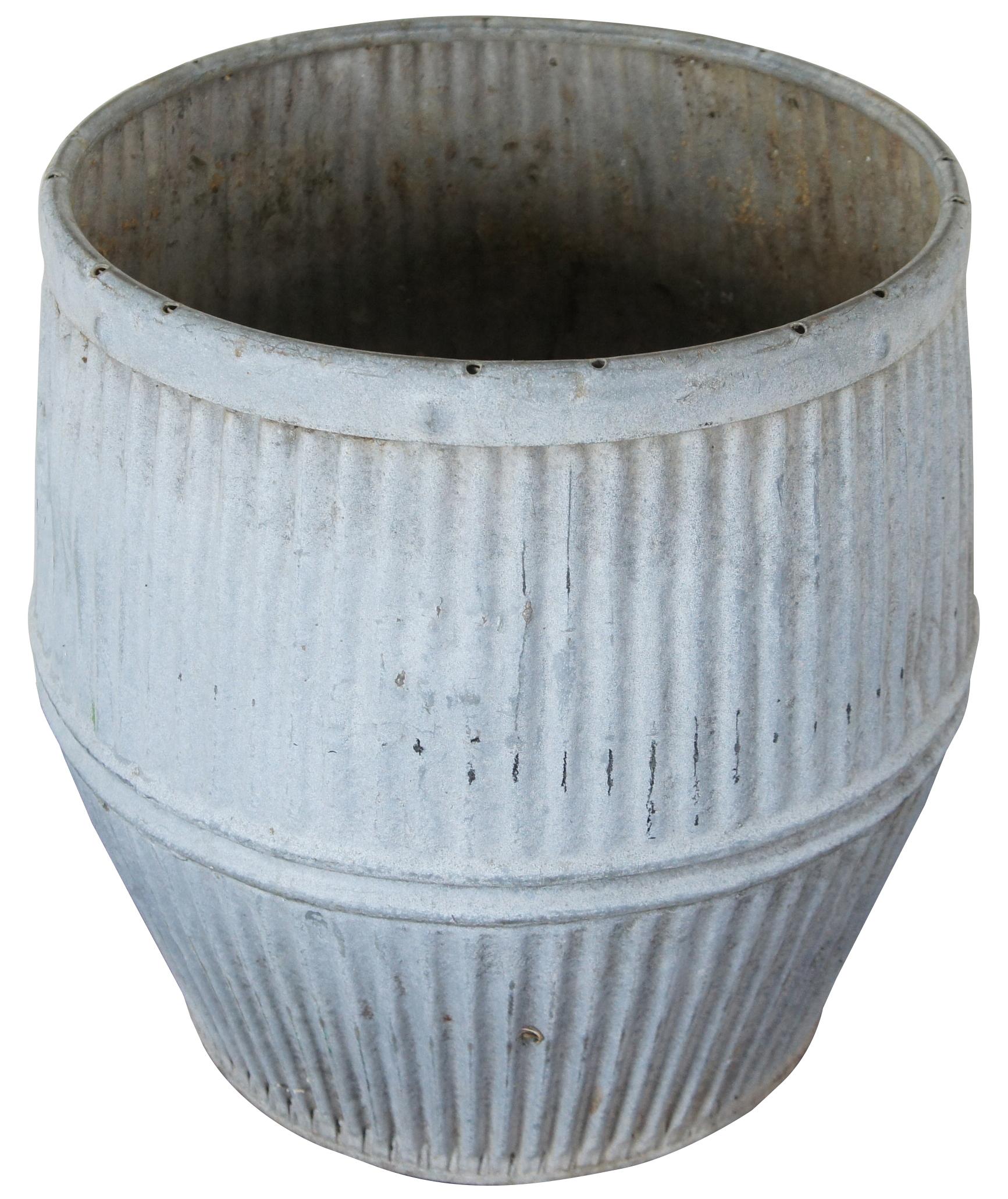 Vintage galvanized zinc wash barrel with tapered ends, corrugated sides and a groove around the middle.
  