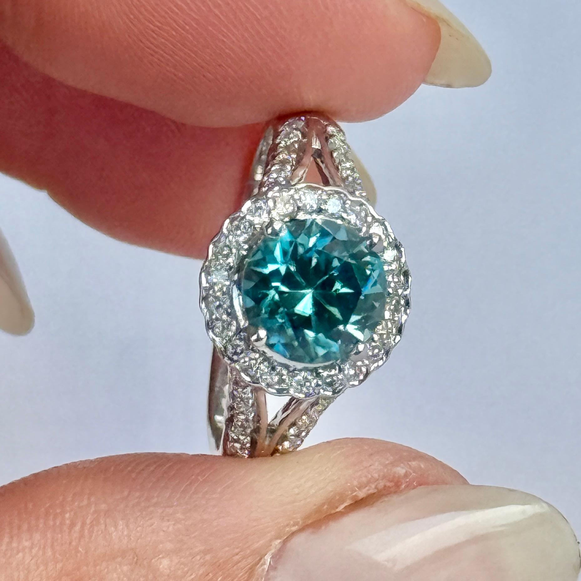 Uno splendido anello da cocktail. Al centro è incastonato un fantastico zircone blu di circa 1,5 carati, circondato da un'aureola di meravigliosi diamanti di circa 2 carati ciascuno. Peso totale dei diamanti circa  75pts. Modello in oro bianco 18
