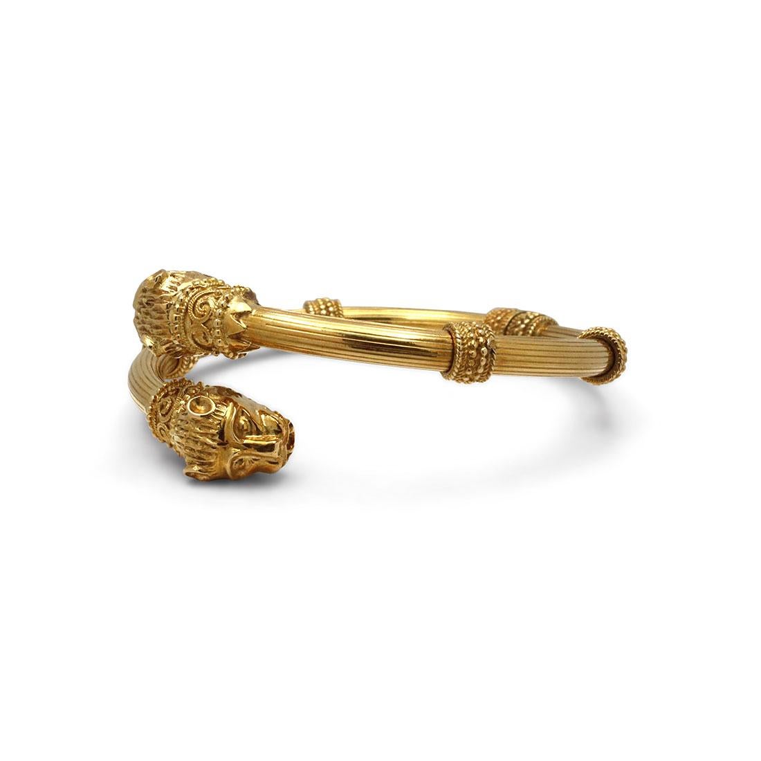 Authentic Zolotas heritage bangle crafted in 18 karat yellow gold features two lion head motifs at each end of the bracelet bypassing one another. The hinged bracelet also features stunning handcrafted textured detail and beadwork and fits up to a 6