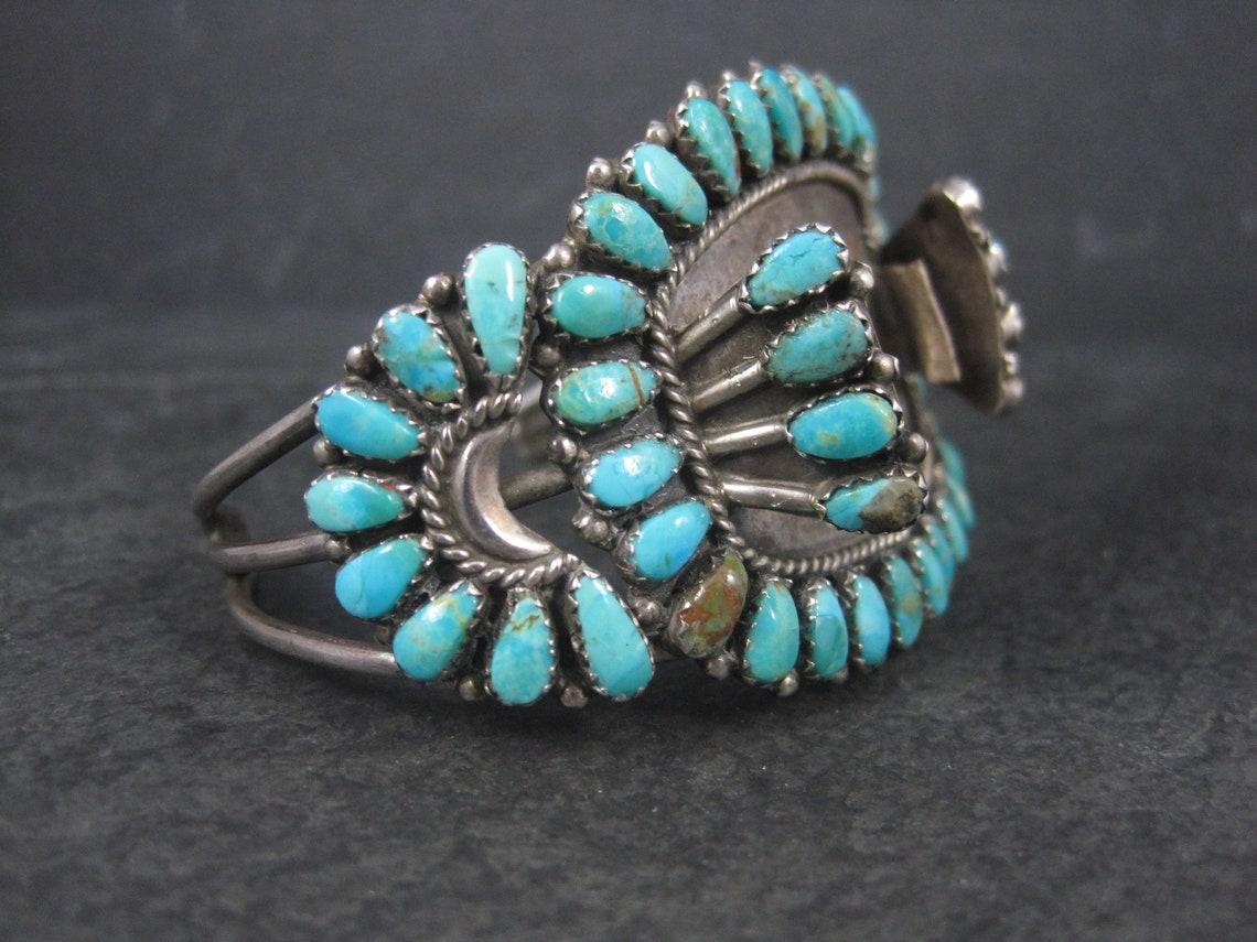 This gorgeous watch band cuff is sterling silver with petit point cut turquoise stones.

The face of this piece measures 1 3/4 inches wide.
It has an inner circumference of 6 1/2 inches including the 1 1/2 inch gap.
Weight: 37.8 grams

Marks: JS